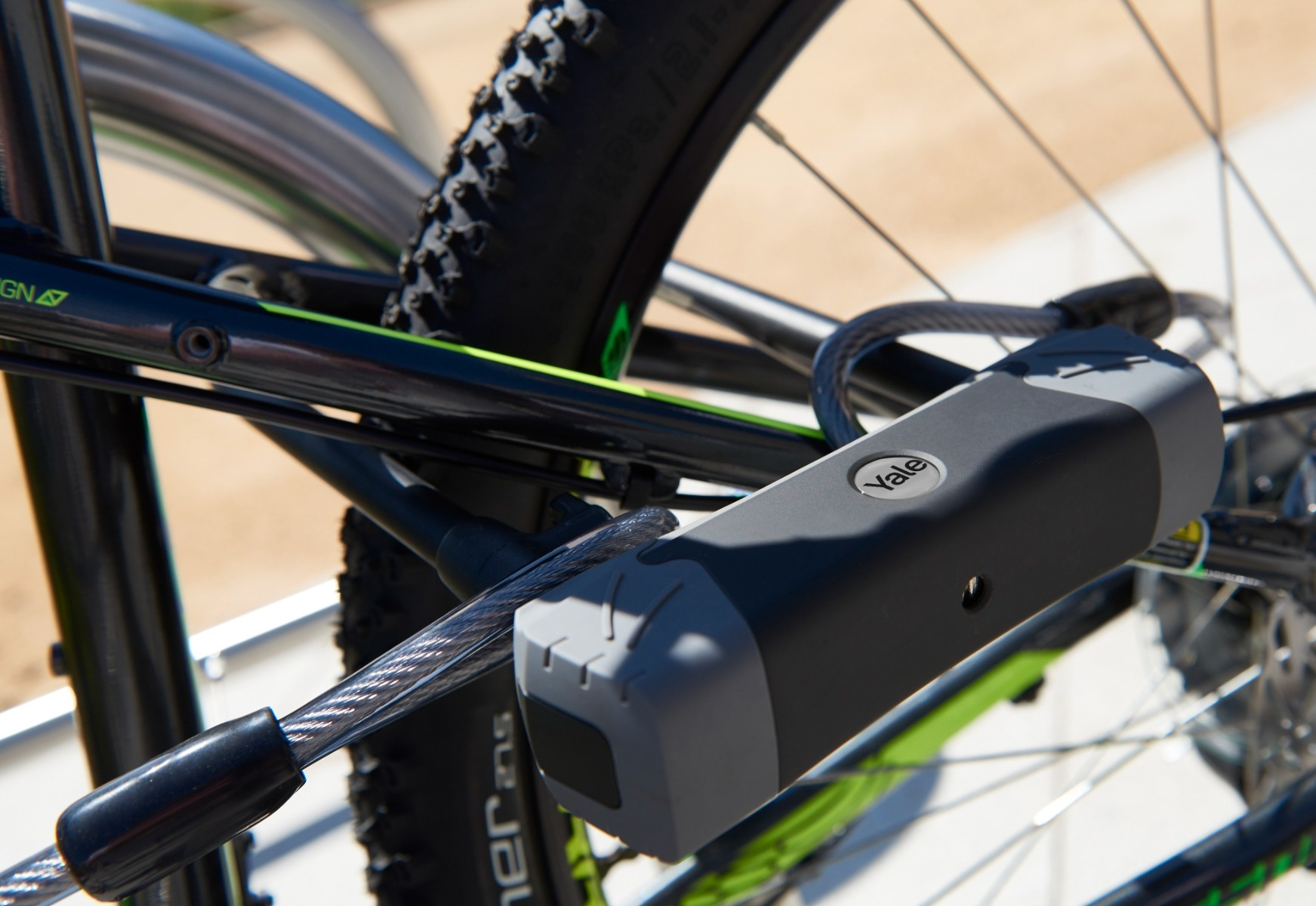 Un candado de bicicleta asegura una bici negra con detalles verdes. Vista de cerca.