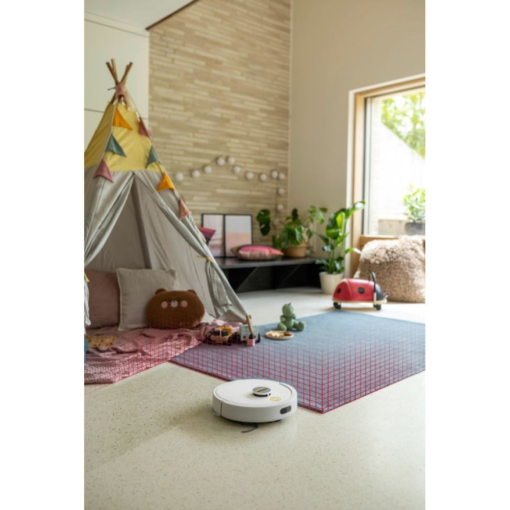 Biały robot sprzątający czyści dywanik do zabawy obok tipi w pokoju dziecka.