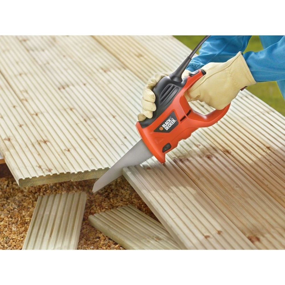 Pomarańczowa piła jest używana przez osobę w rękawiczkach do cięcia drewnianych desek.