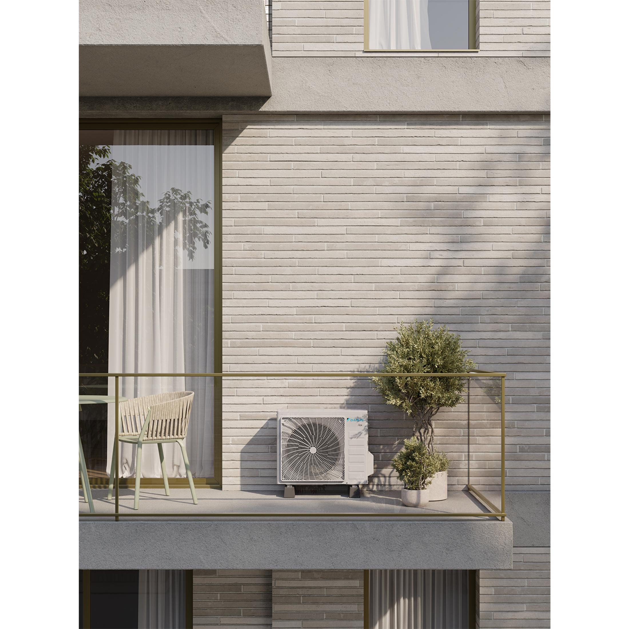 Un'unità di condizionamento si trova su un balcone accanto a un ulivo.