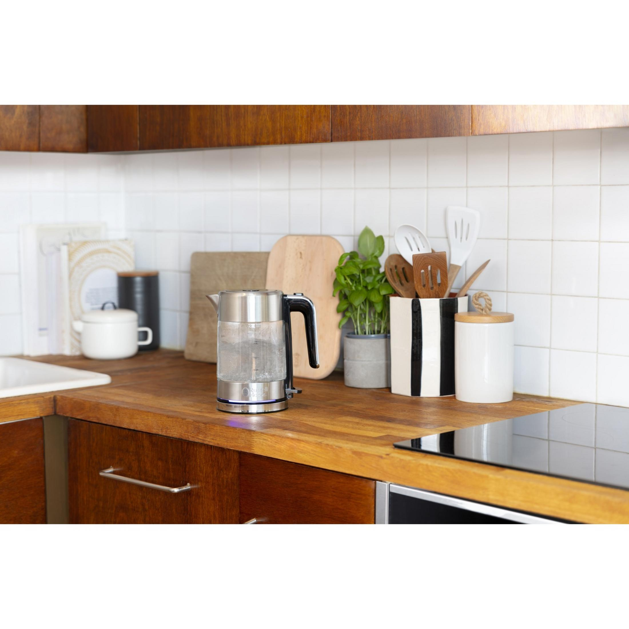 Srebrny czajnik z czarną rączką stoi na drewnianym blacie.