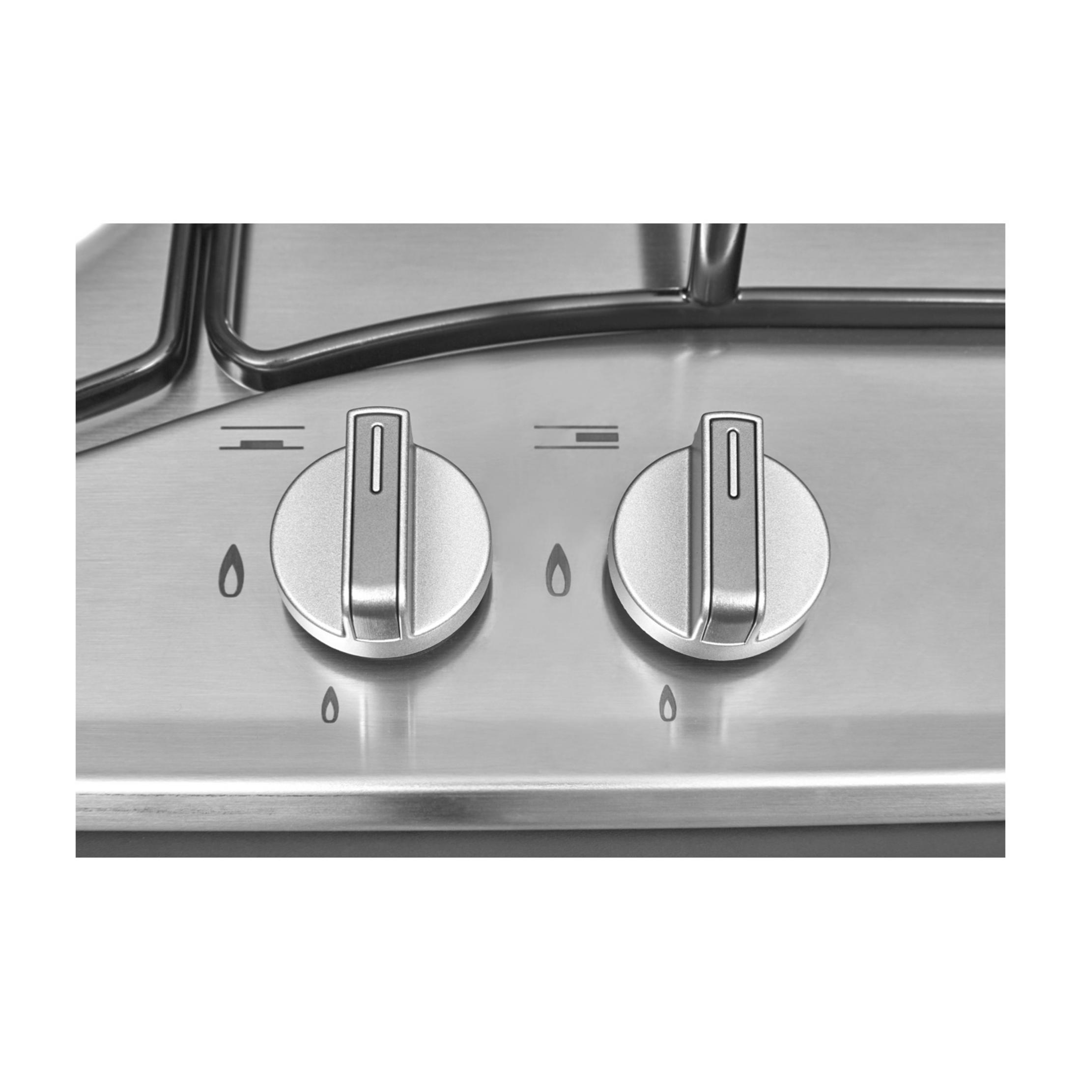 Dwa srebrne pokrętła na kuchence gazowej z symbolami płomienia.