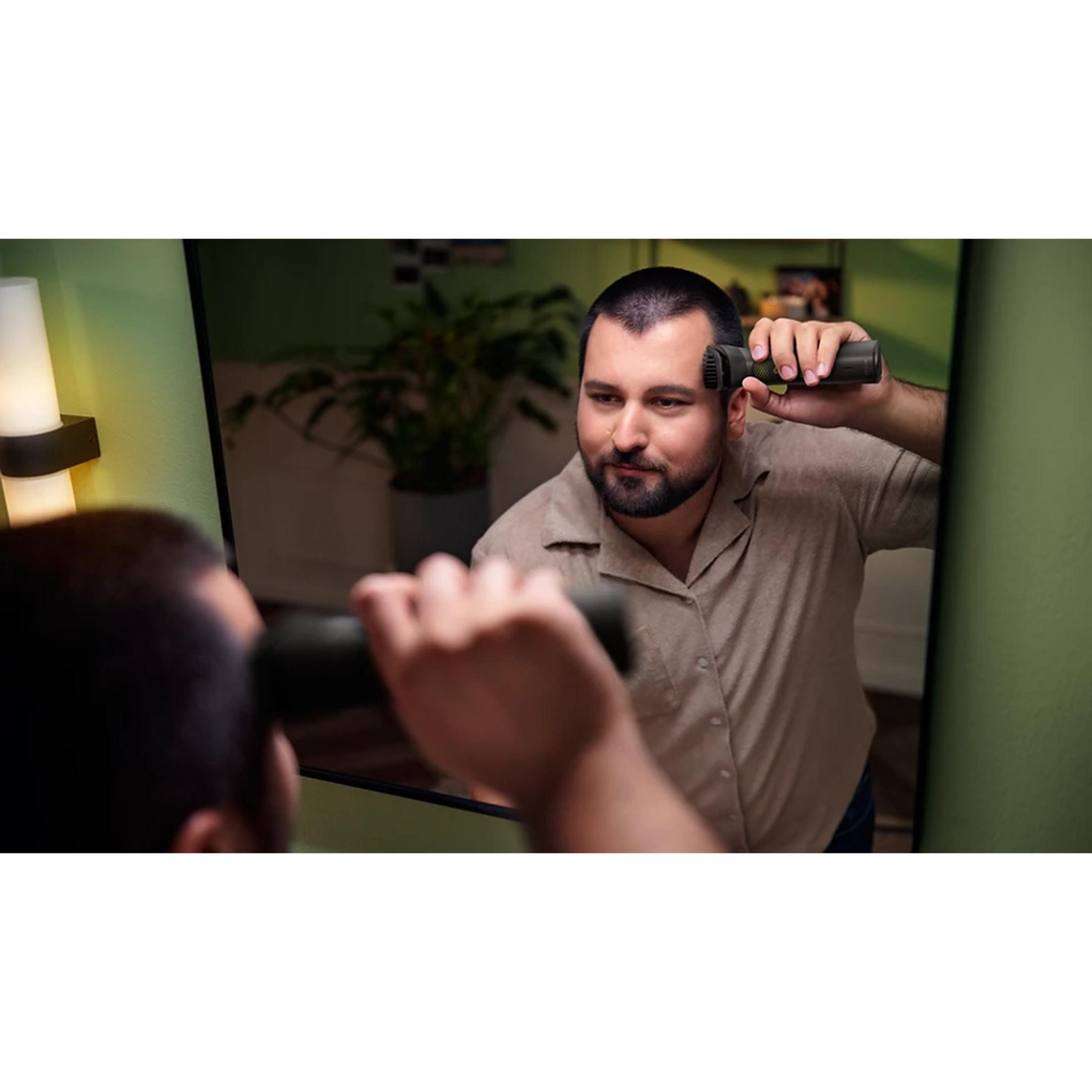 Un hombre usa una recortadora en el espejo. Habitación verde con lámpara.