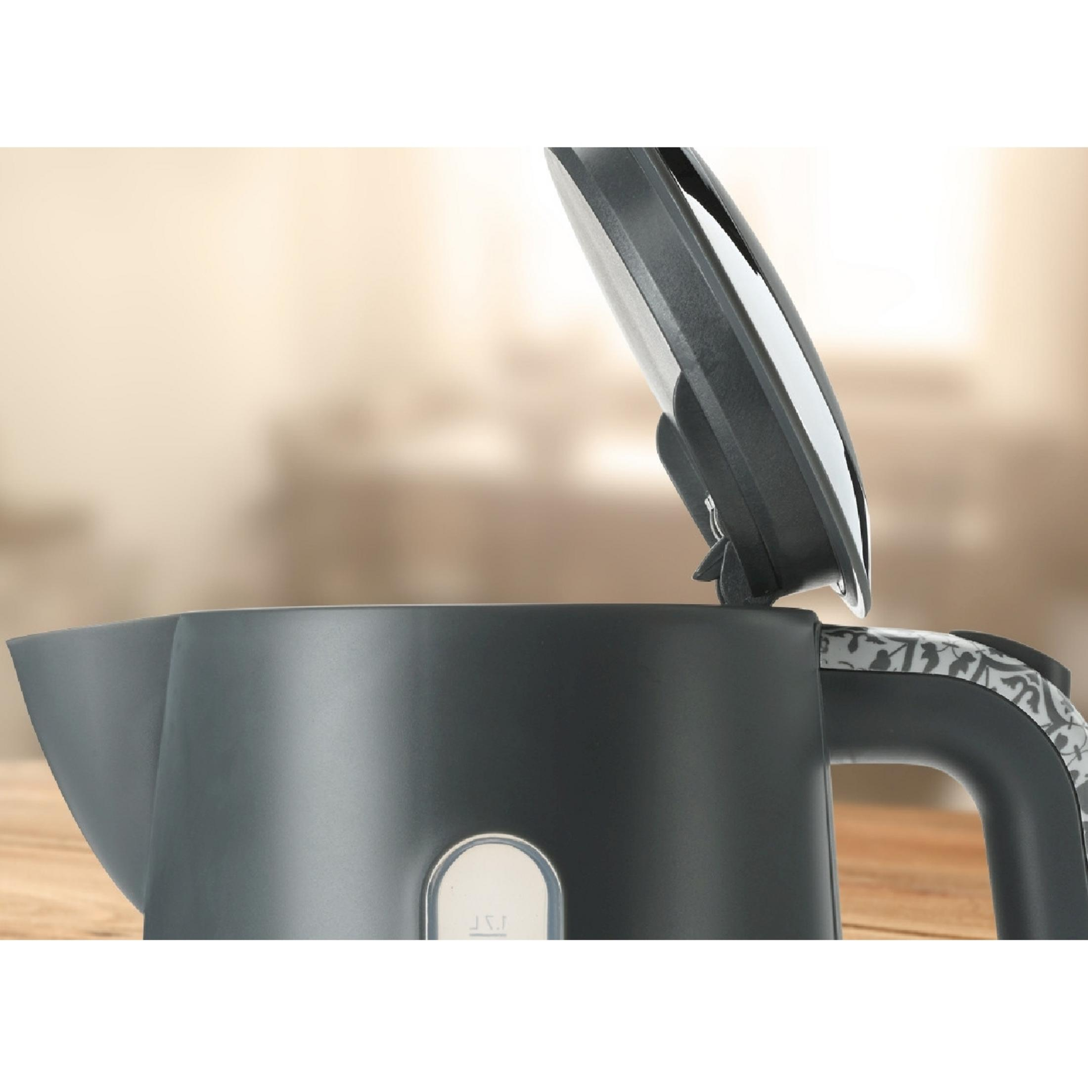 A black kettle with its lid open stands on a wooden table.