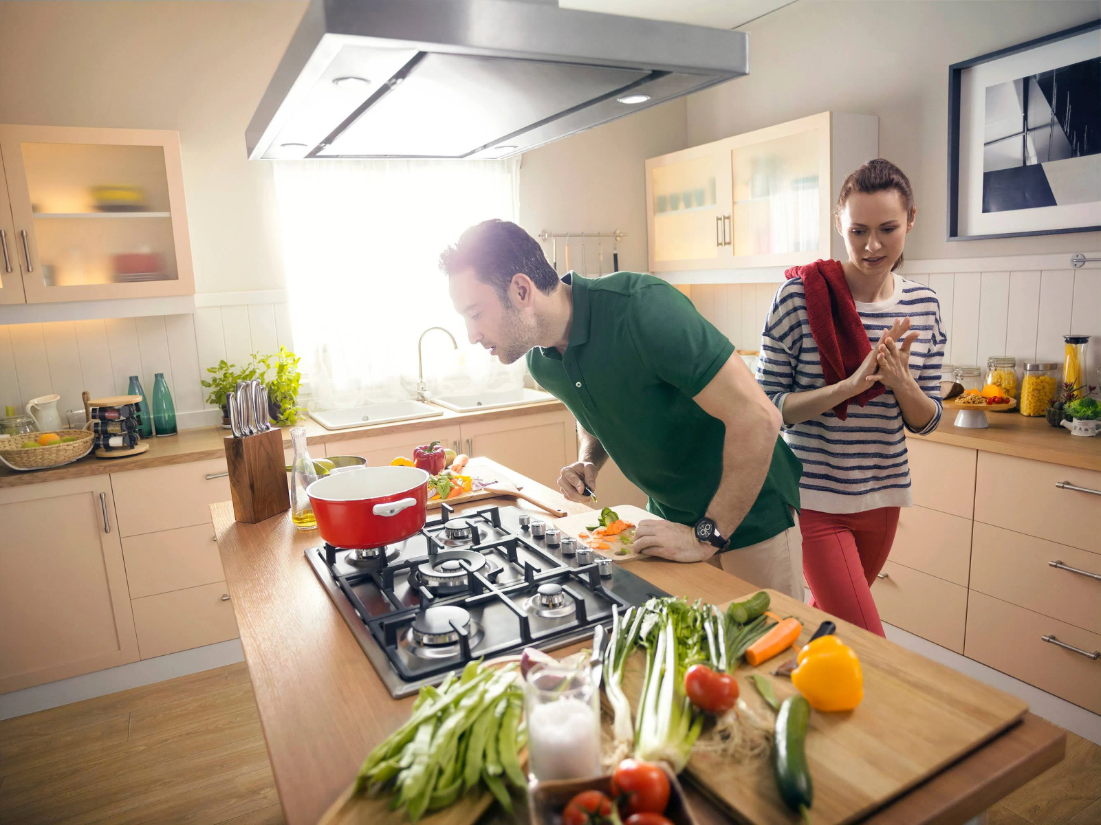 Mężczyzna gotuje, kobieta patrzy. Świeże warzywa na blacie.