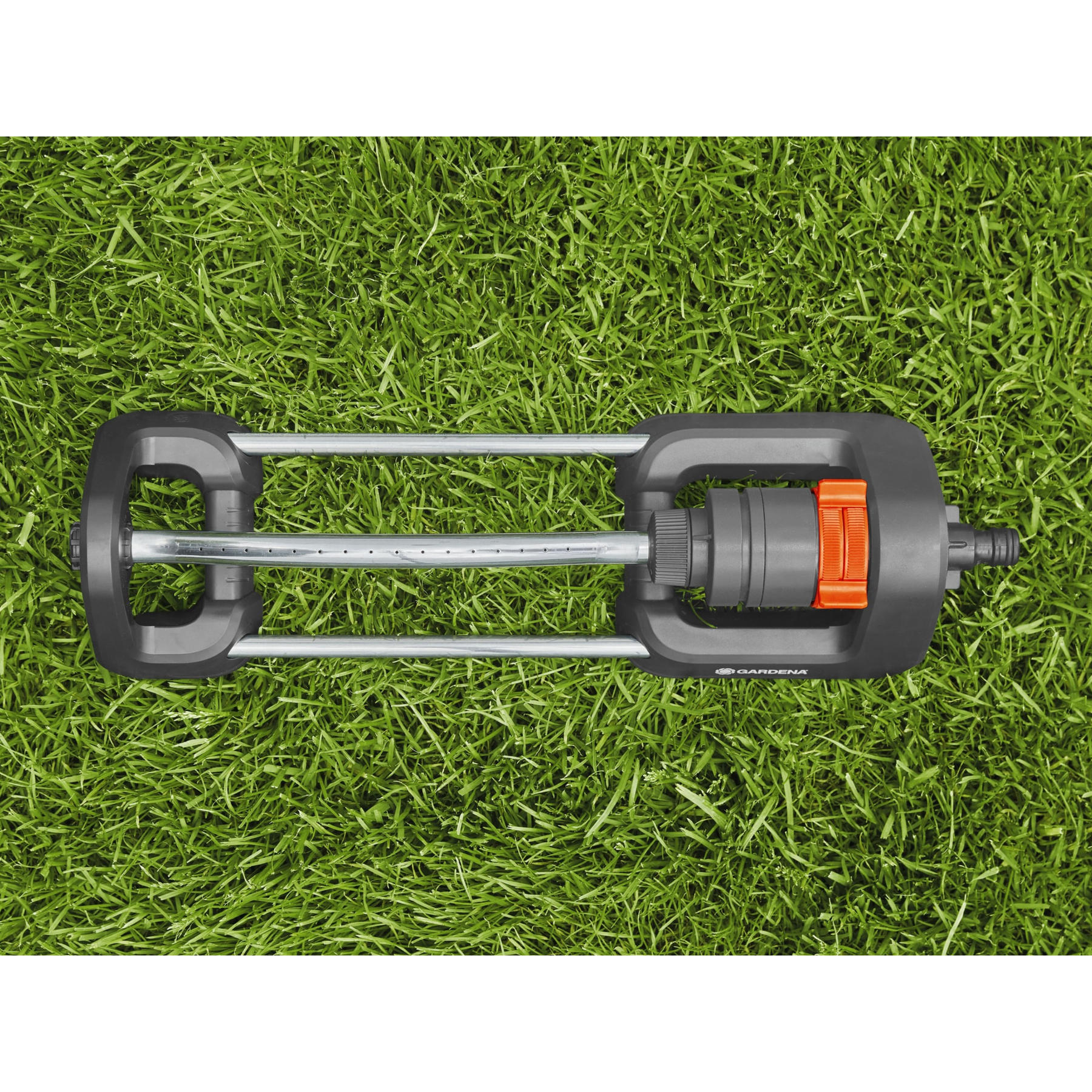 Ein Sprinkler liegt auf einem grünen Rasen. Er ist grau mit orangen Akzenten.