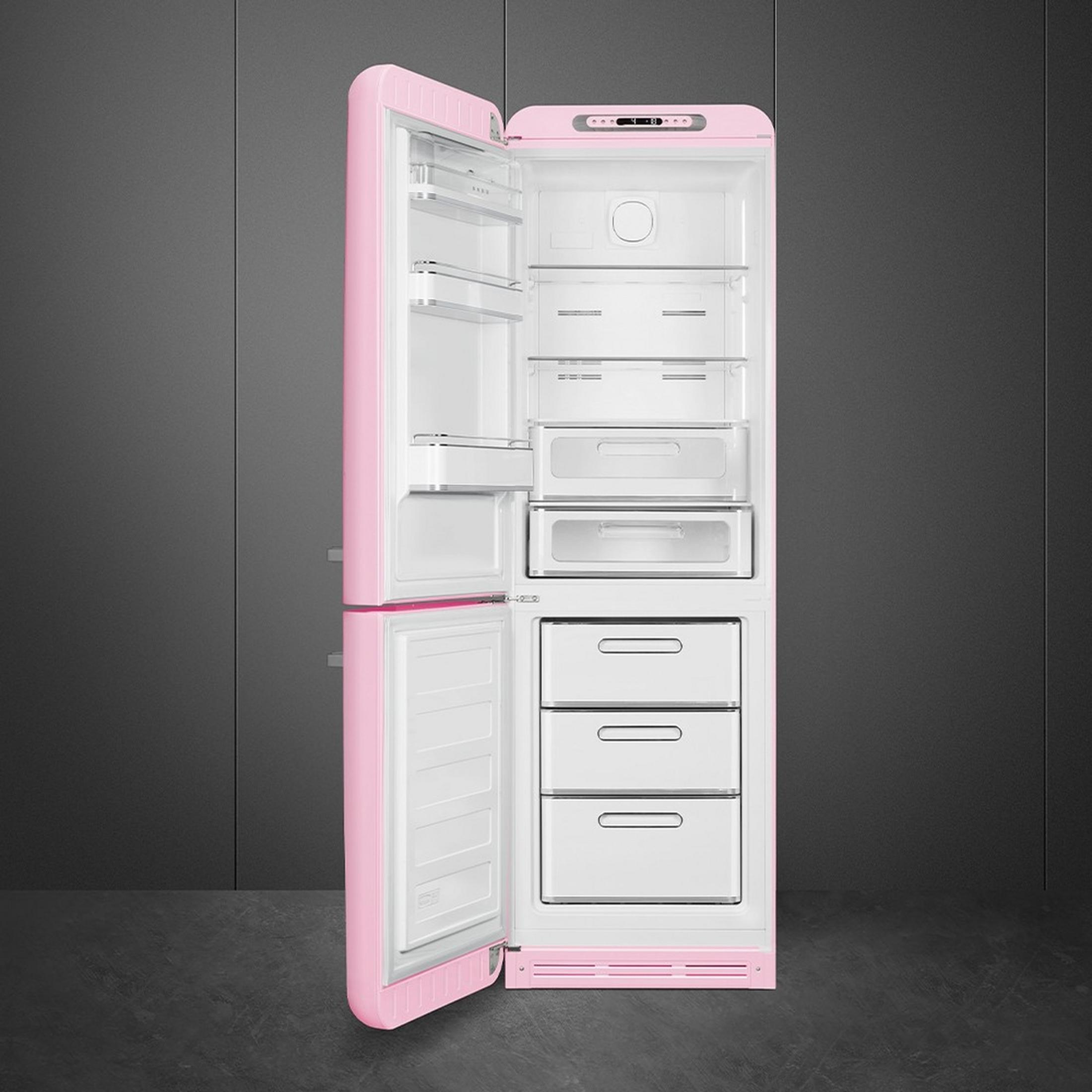 Un refrigerador rosa abierto con cajones y estantes blancos.