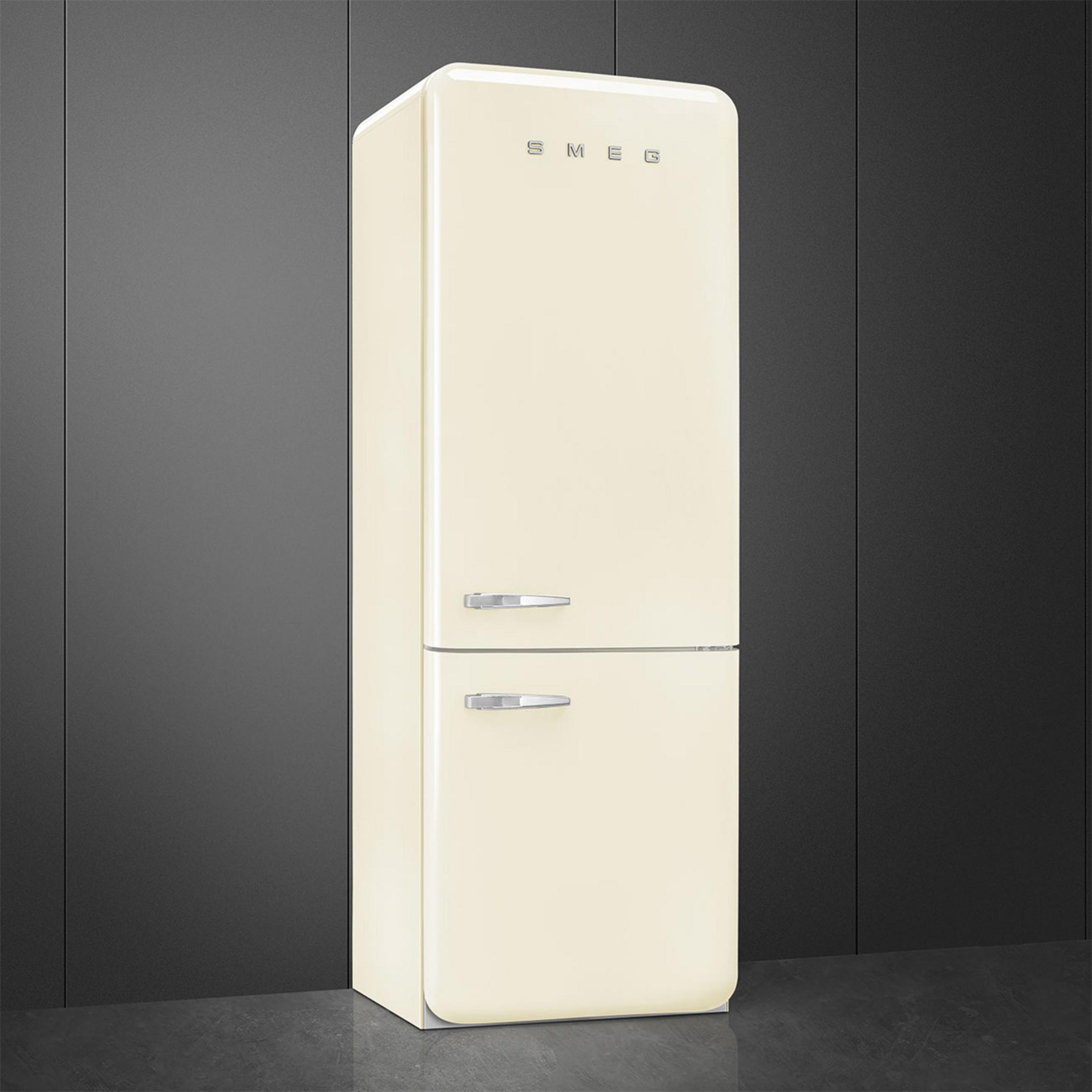 Un refrigerador color crema con dos tiradores plateados se alza sobre un suelo oscuro.