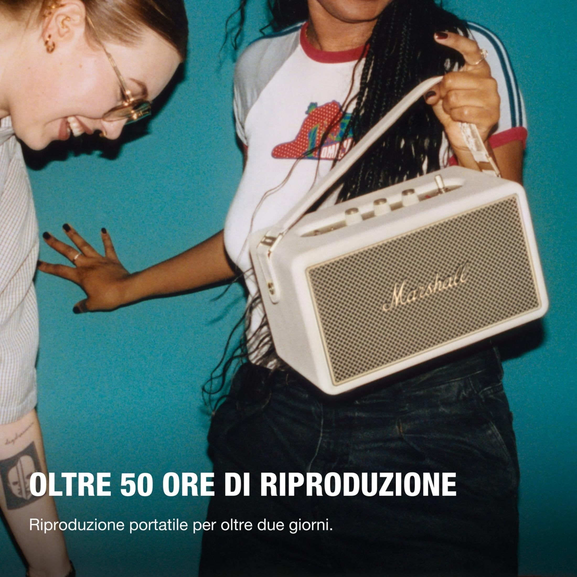 Due donne in piedi su sfondo blu. Una tiene una borsa.