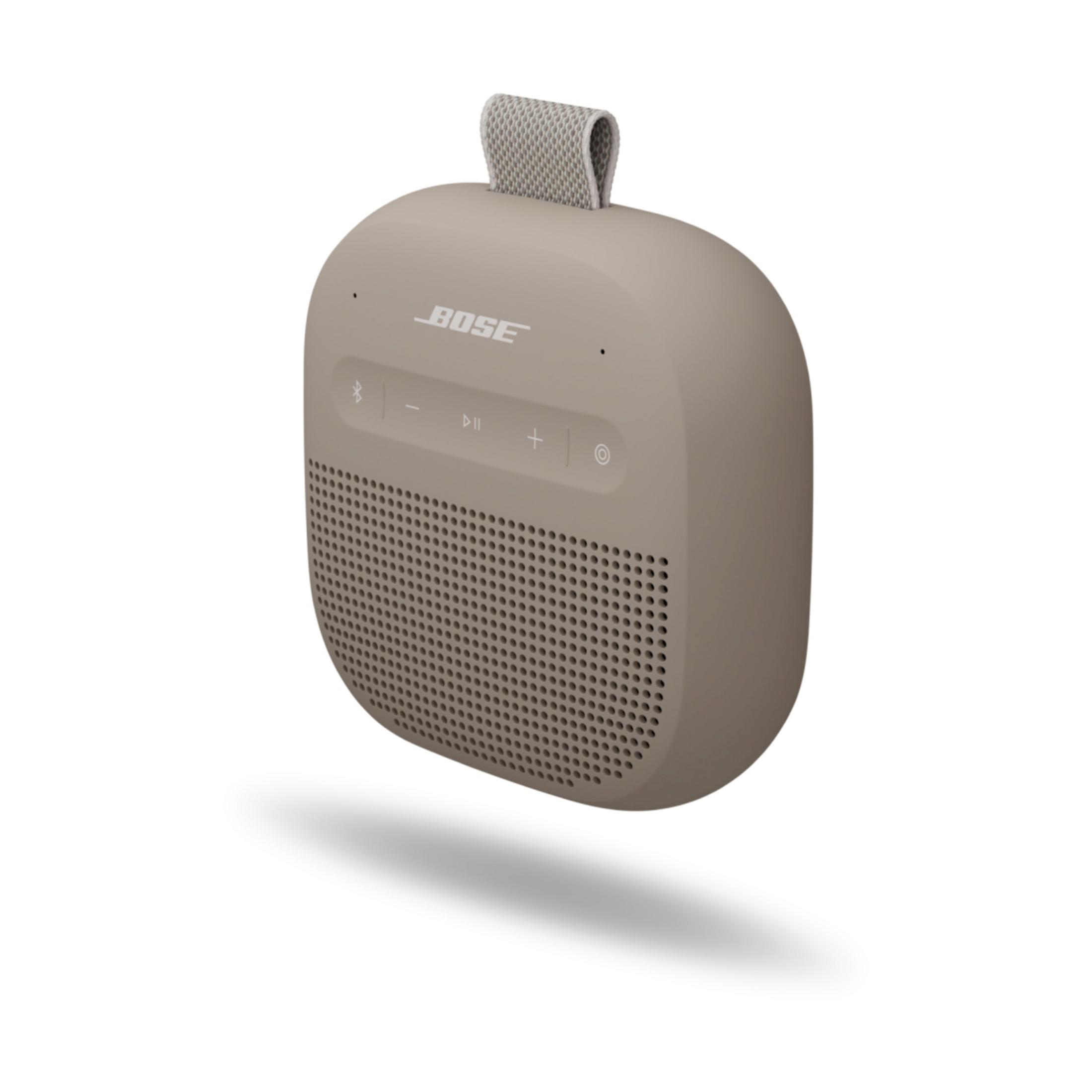 Un altavoz Bose beige con asa de tela y botones de control.