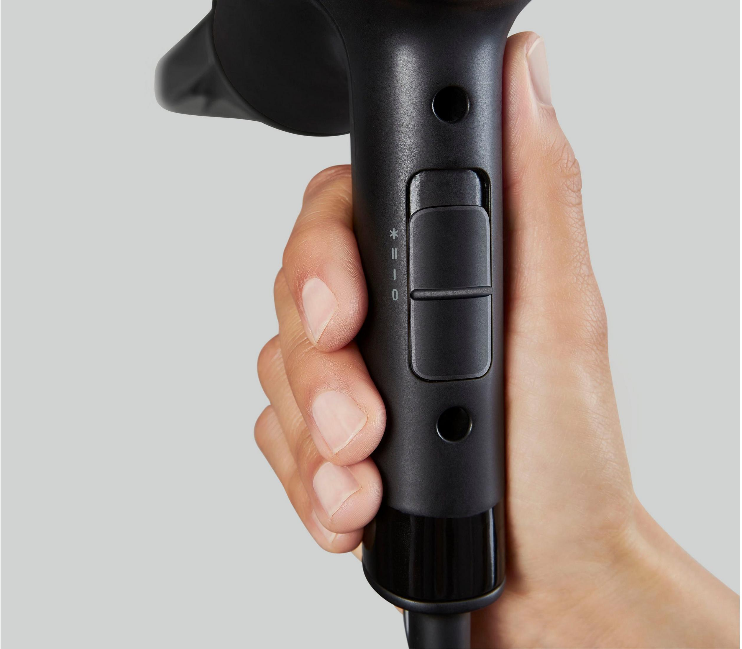 Ręka trzyma czarną suszarkę do włosów z kontrolkami.