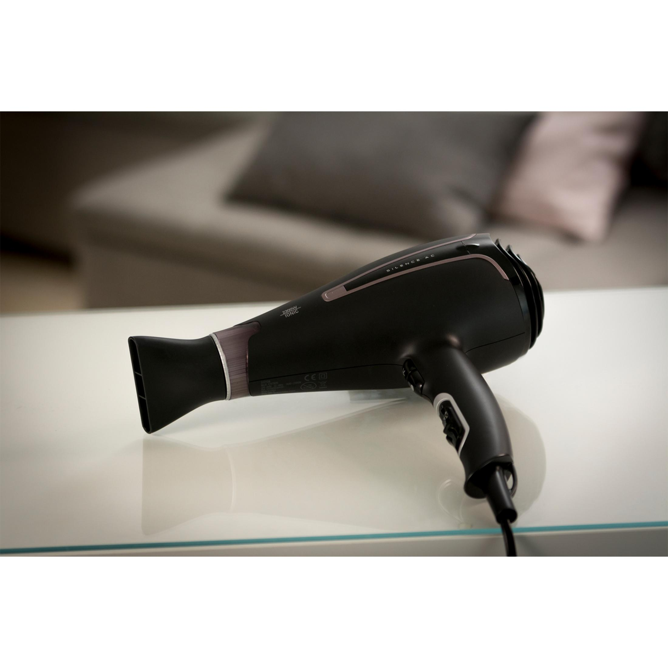 Czarna suszarka do włosów z srebrnymi akcentami na białym stole.