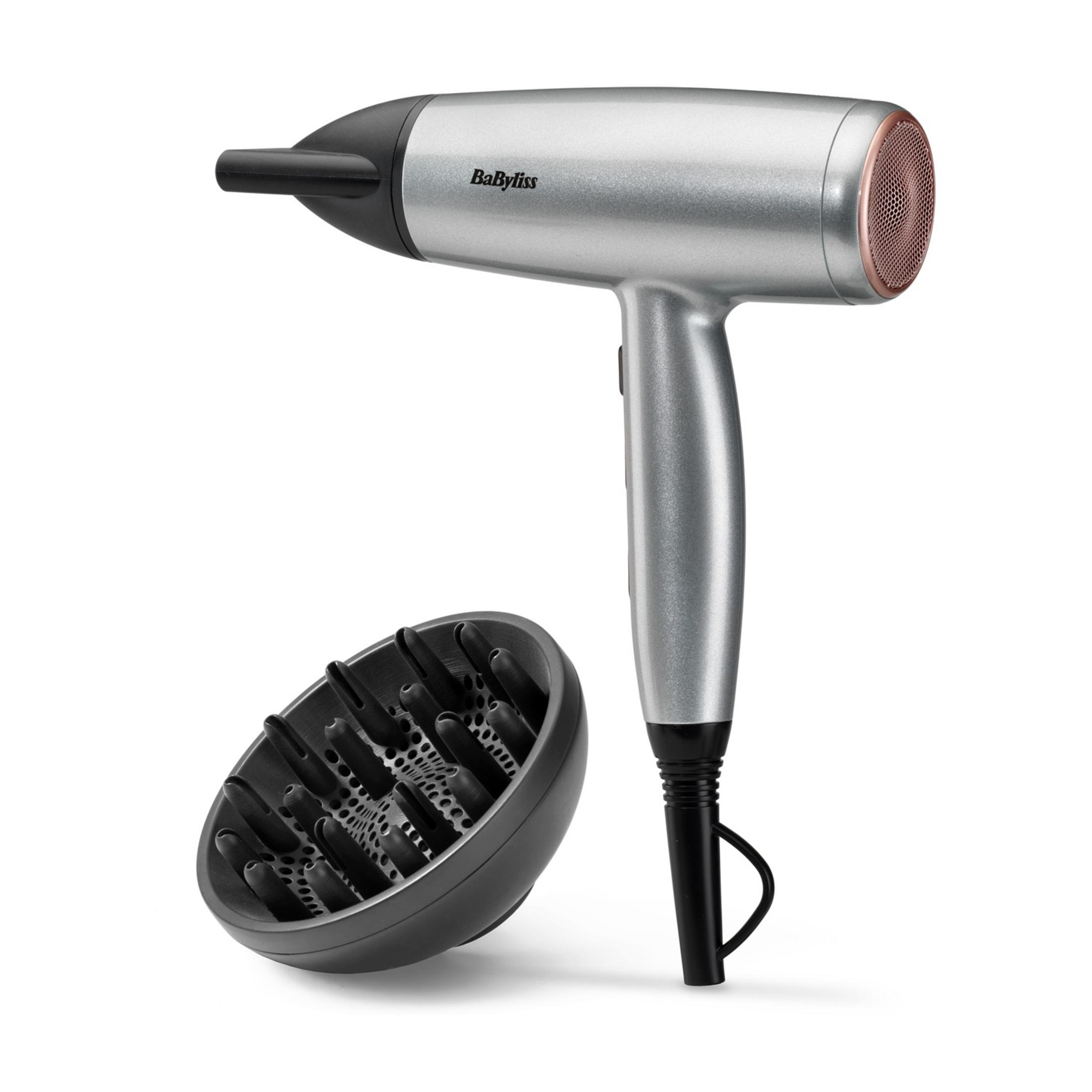 Srebrna suszarka do włosów z czarną dyszą i dyfuzorem na białym tle.