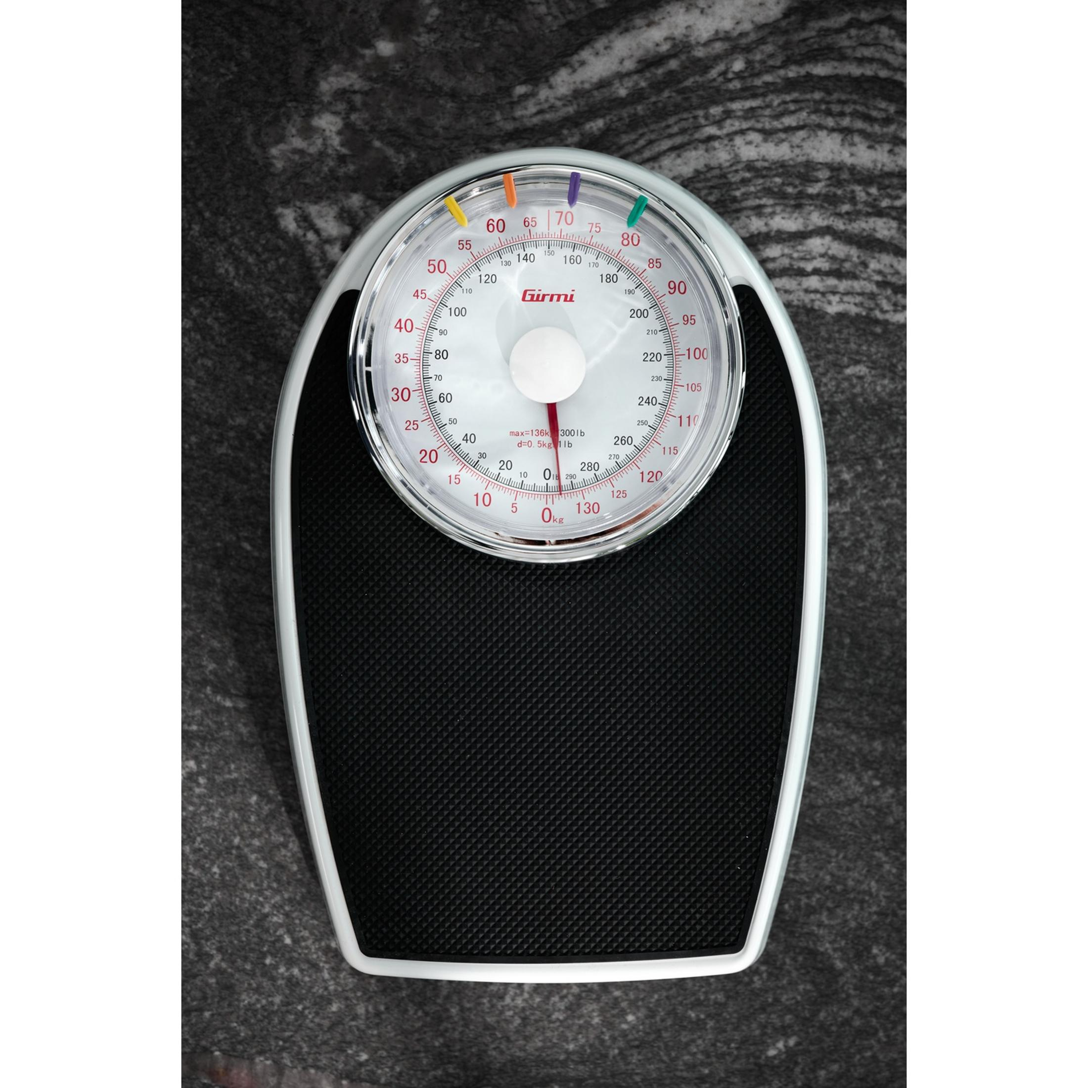 Waga analogowa z czarną platformą i okrągłą tarczą wskazującą wagę w kg/lb.