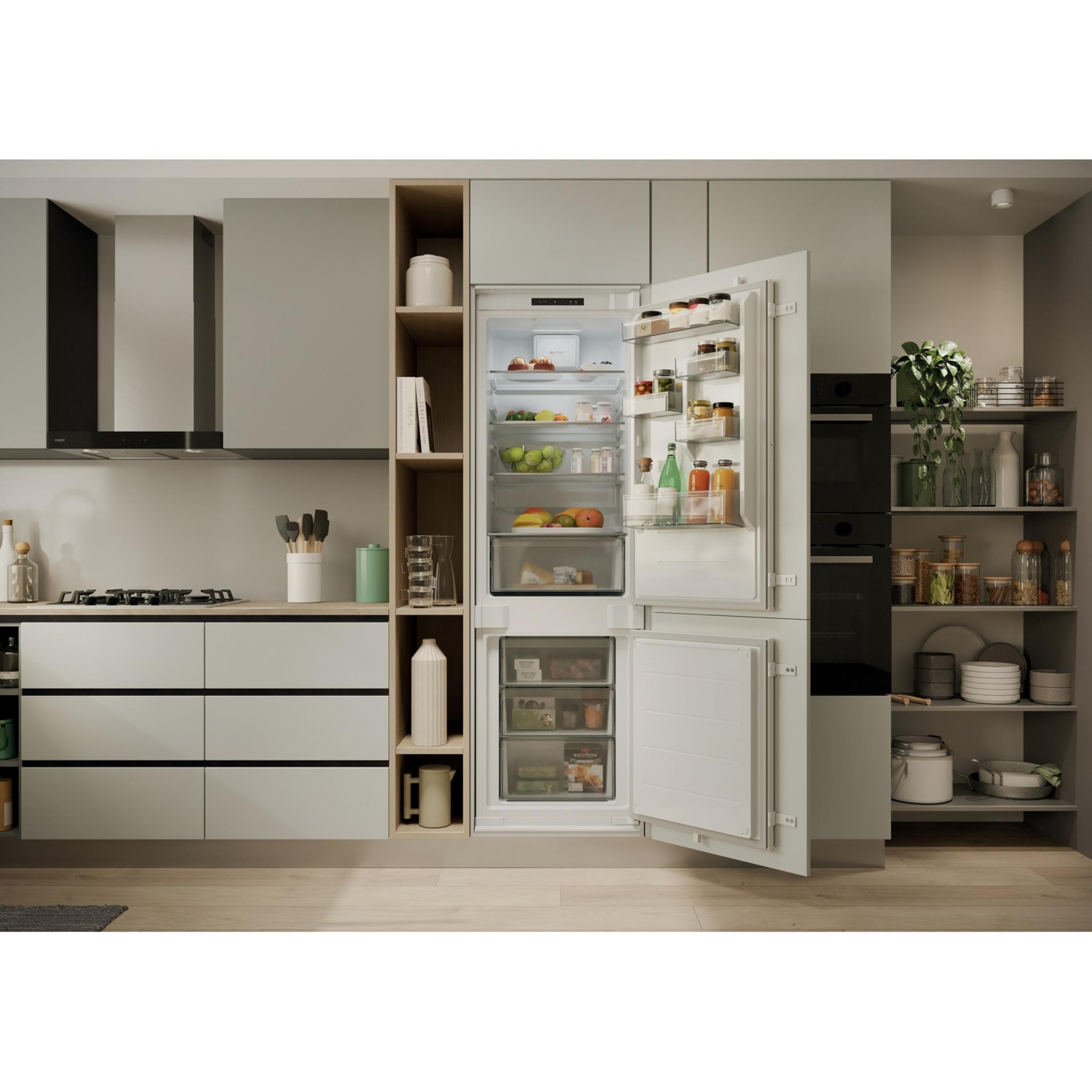 Cocina moderna con refrigerador abierto, lleno de comida y fruta.