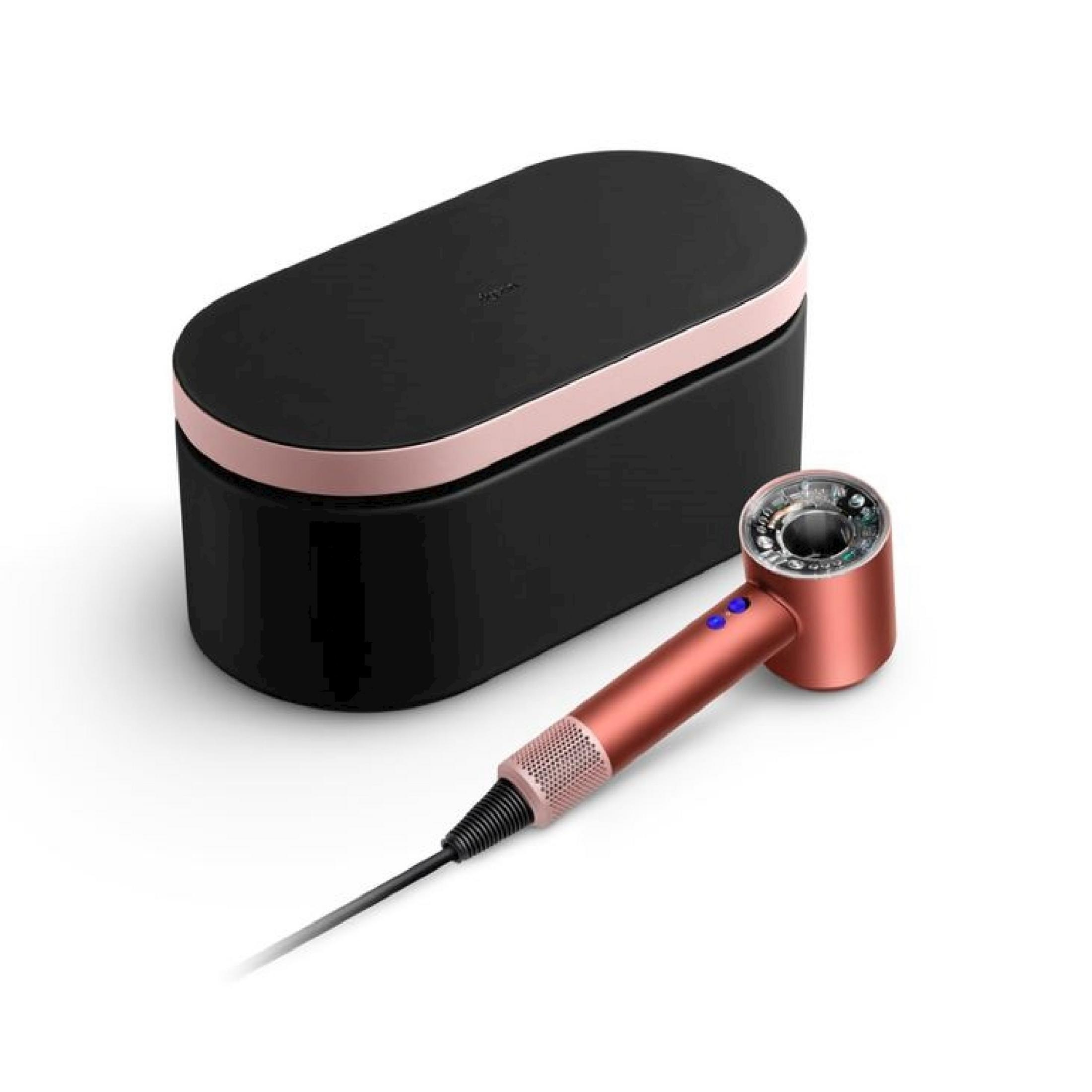 Miedziana suszarka do włosów leży obok czarnego etui z miedzianym wykończeniem.