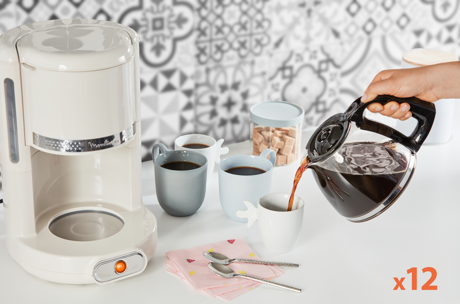 Ekspres do kawy nalewa kawę do filiżanek. Widoczny jest pojemnik na cukier.