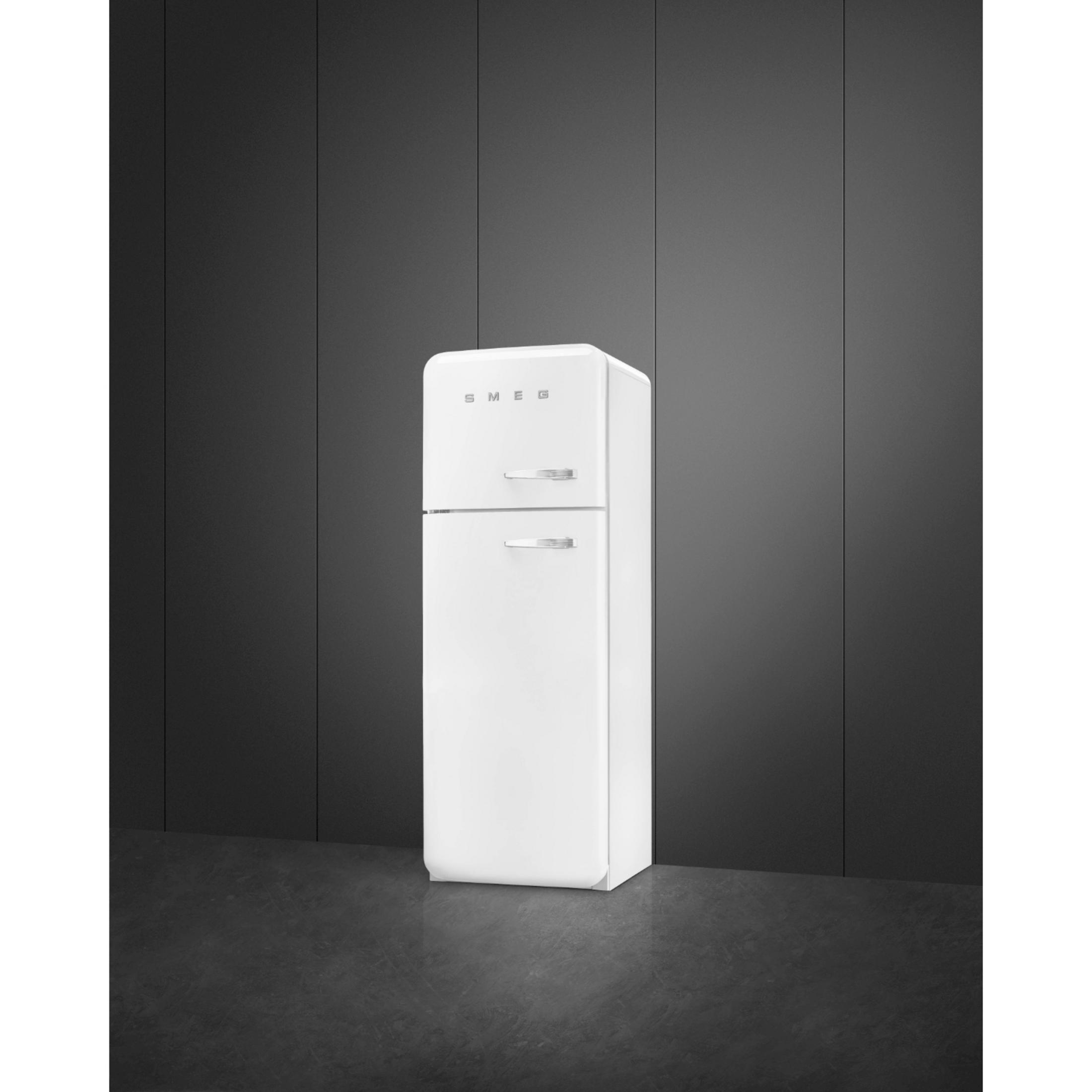 Un frigorífico SMEG blanco sobre suelo oscuro frente a pared oscura.