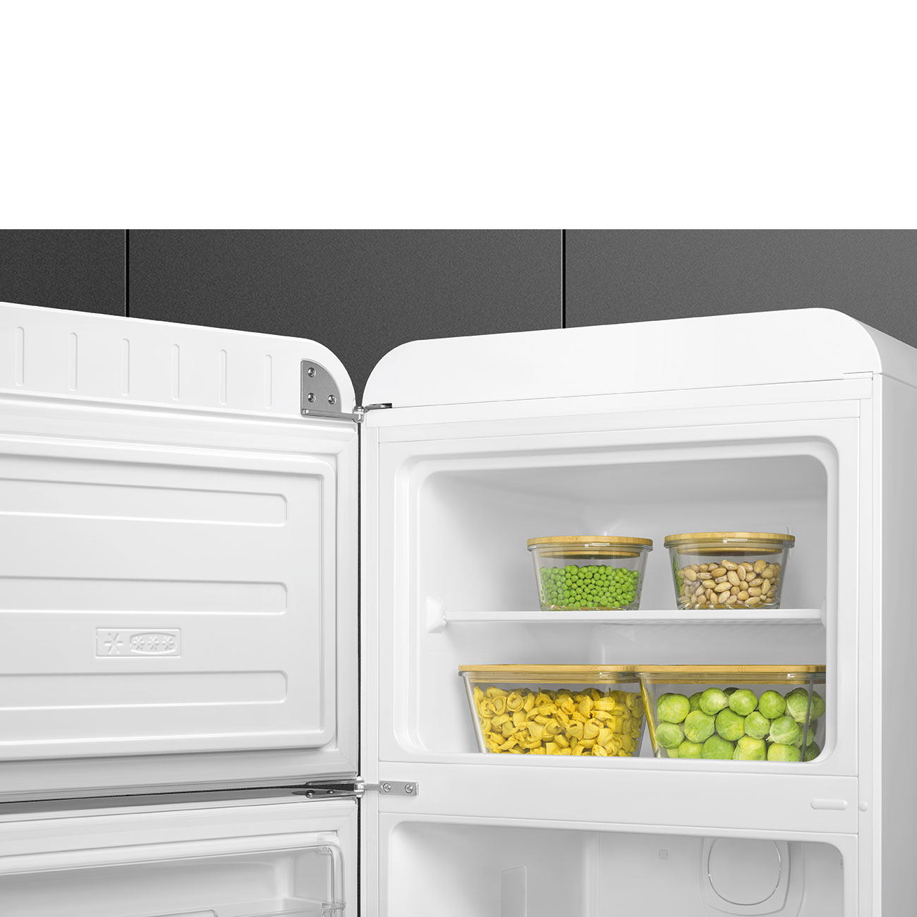 Un refrigerador abierto con cuatro recipientes llenos de guisantes, frijoles, pasta y coles de Bruselas.