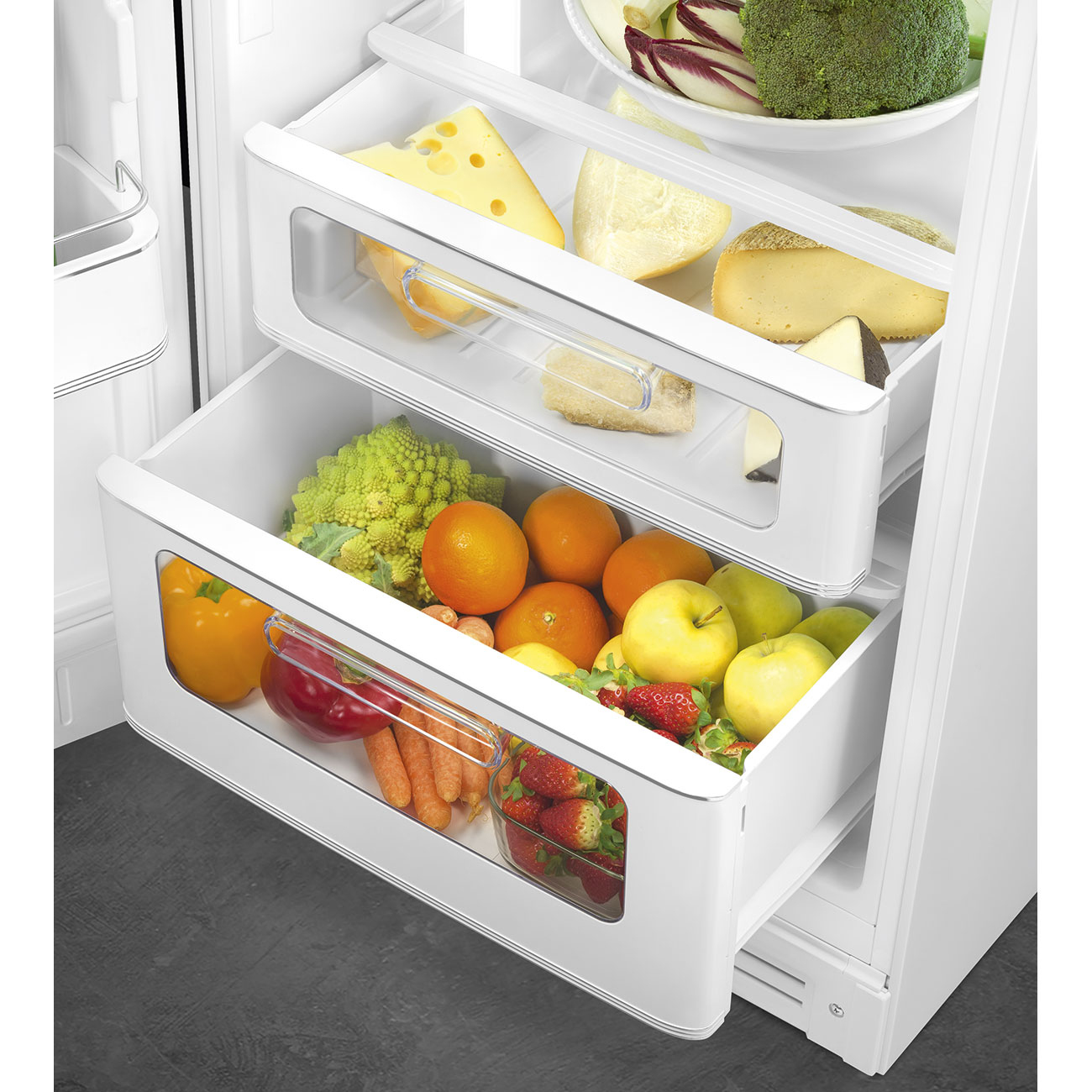 Dos cajones abiertos del refrigerador llenos de queso, frutas, verduras y fresas.