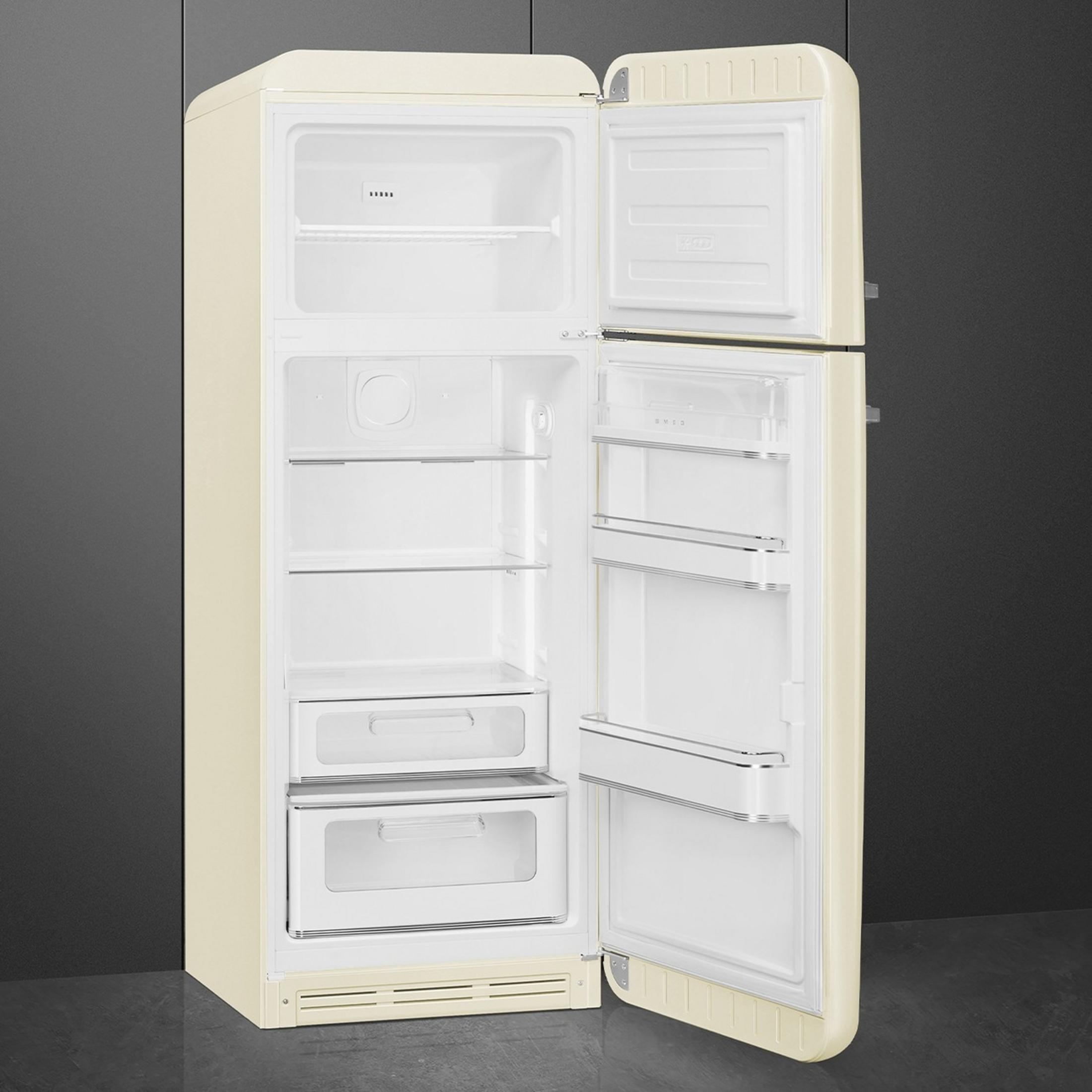 Un refrigerador color crema con la puerta abierta está sobre un suelo oscuro contra una pared oscura.