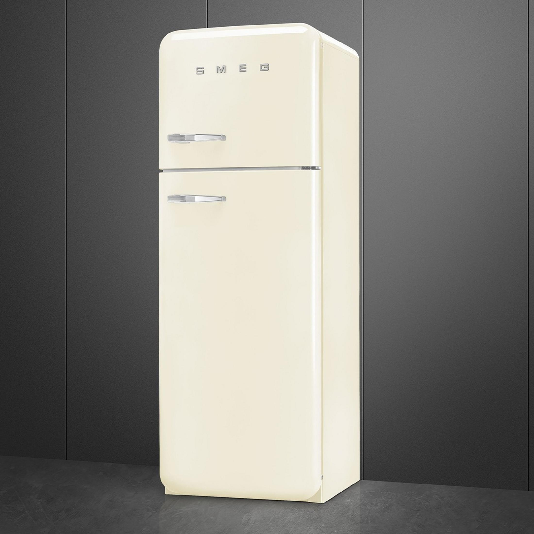 Un refrigerador color crema de dos puertas con tiradores plateados sobre suelo oscuro.