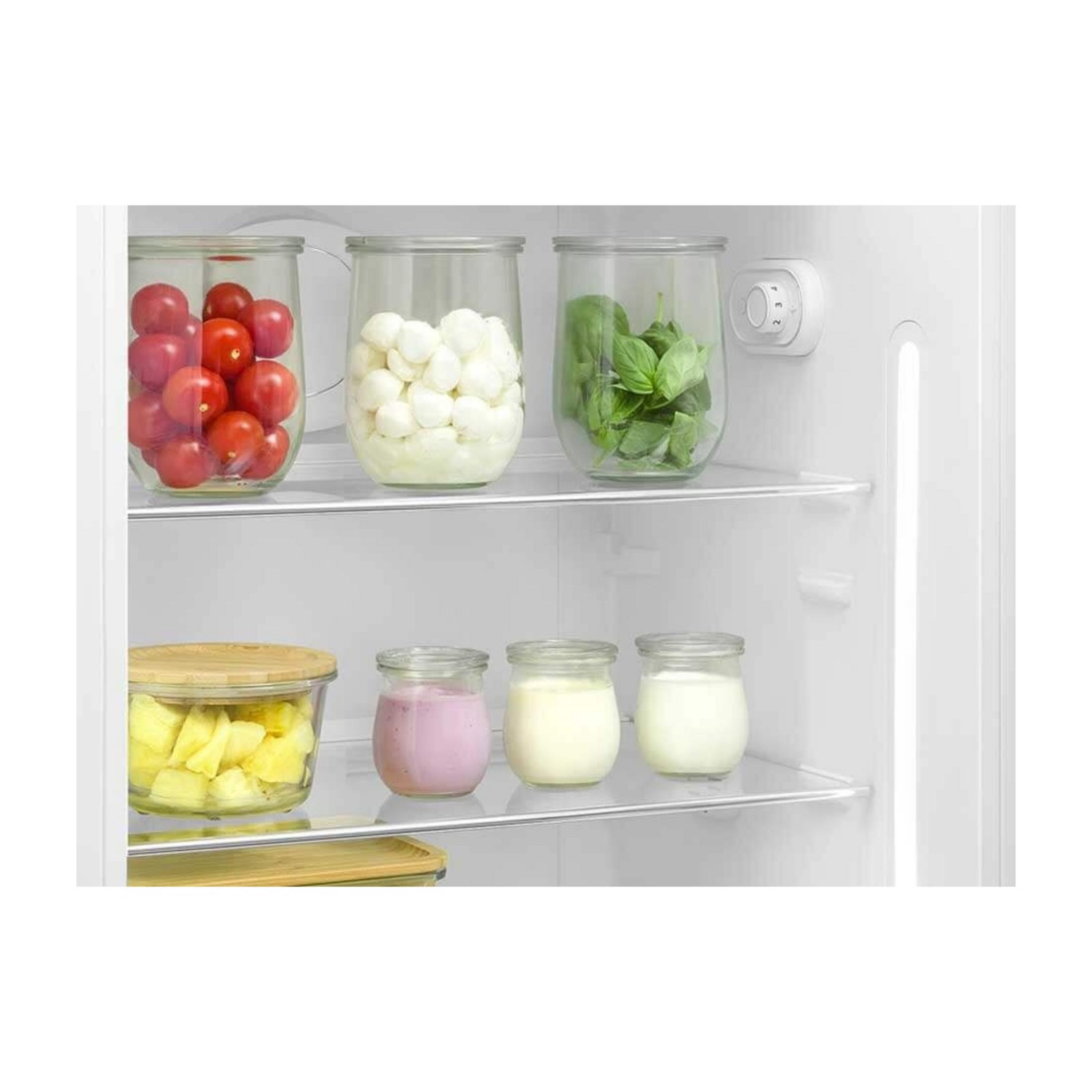 Una repisa de refrigerador con frascos de tomates, mozzarella, albahaca y yogur.