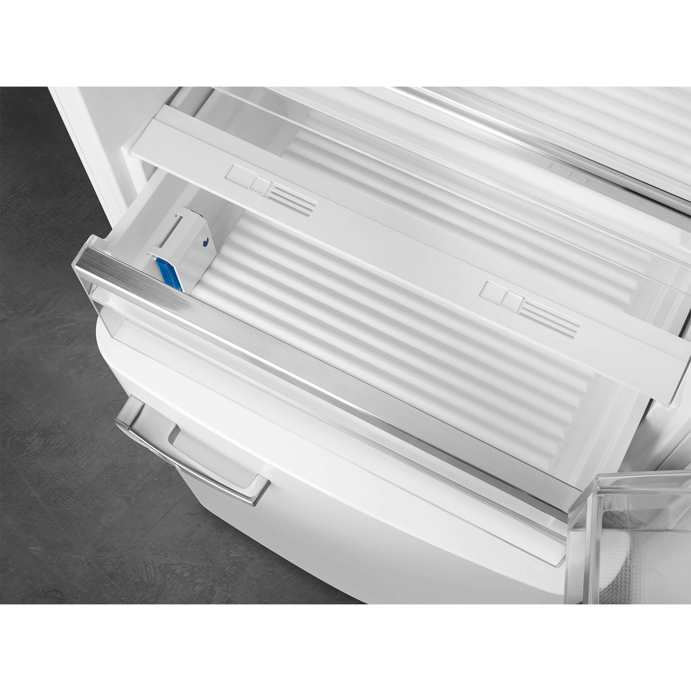 Un refrigerador abierto con cajones de plástico blanco y tirador metálico.