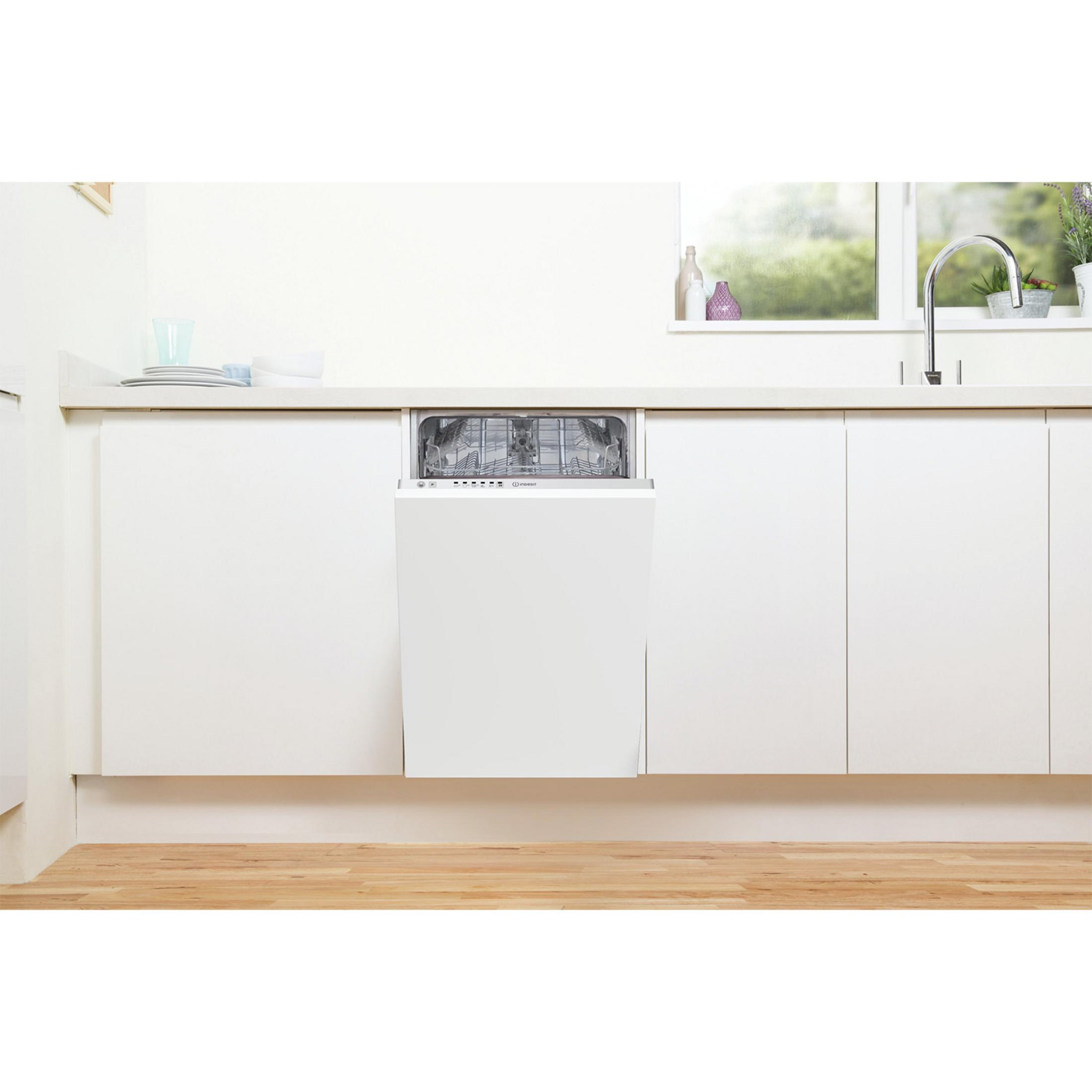 Un lavavajillas blanco con la puerta abierta, empotrado en una unidad de cocina blanca.