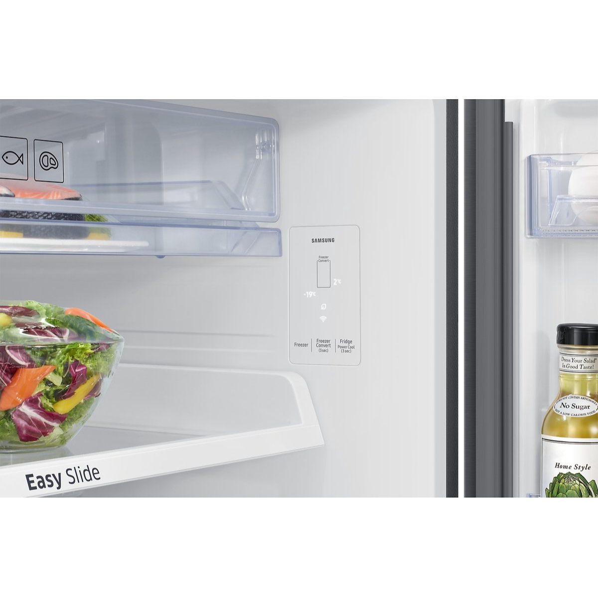 Interno di un frigorifero con insalata, pesce, bottiglie e pannello Samsung.