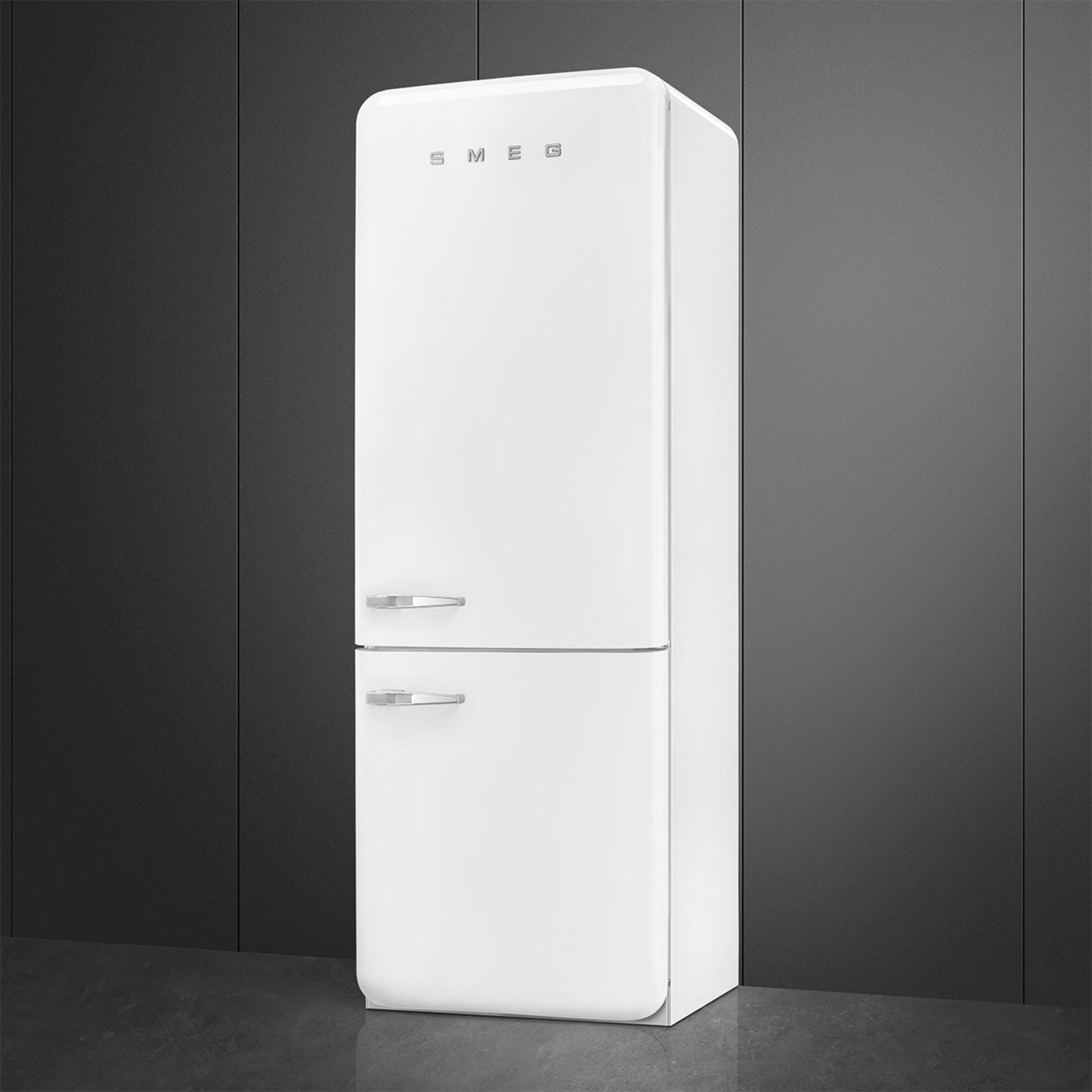 Un frigorífico Smeg blanco con tiradores plateados sobre suelo oscuro.