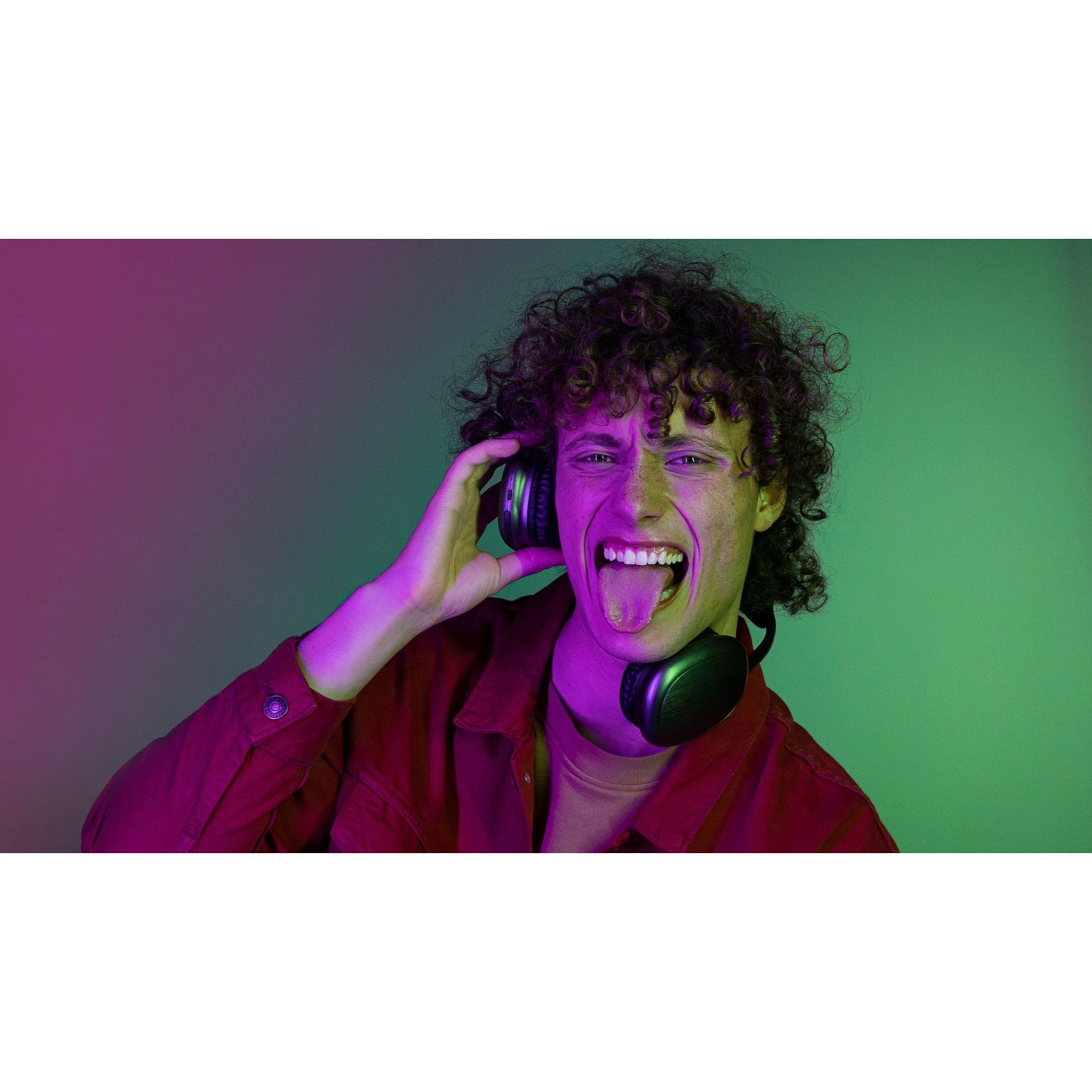 Mężczyzna w słuchawkach, wystawia język, w czerwonej kurtce, tło fioletowo-zielone.