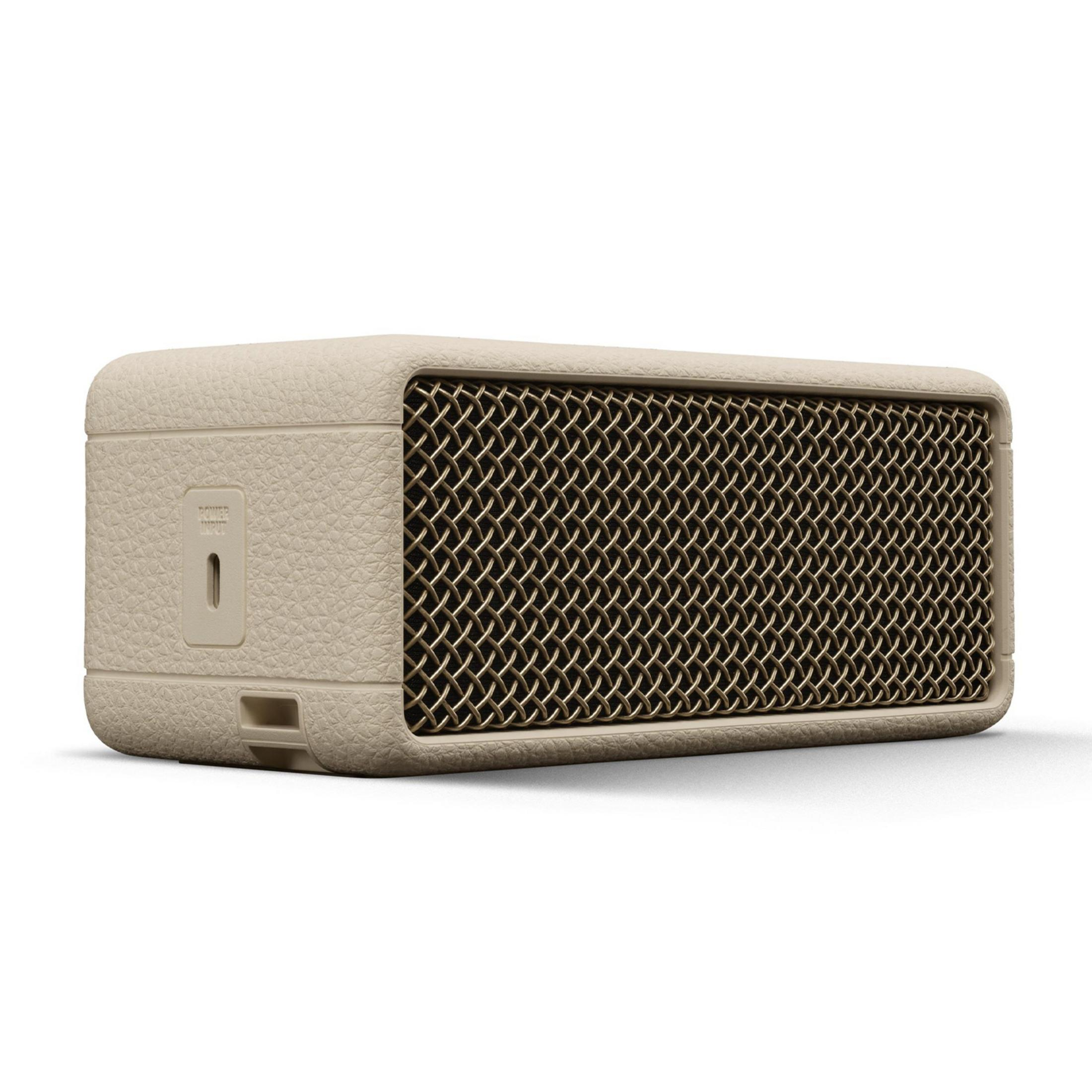 Un altavoz beige con rejilla dorada y puerto de entrada de corriente.