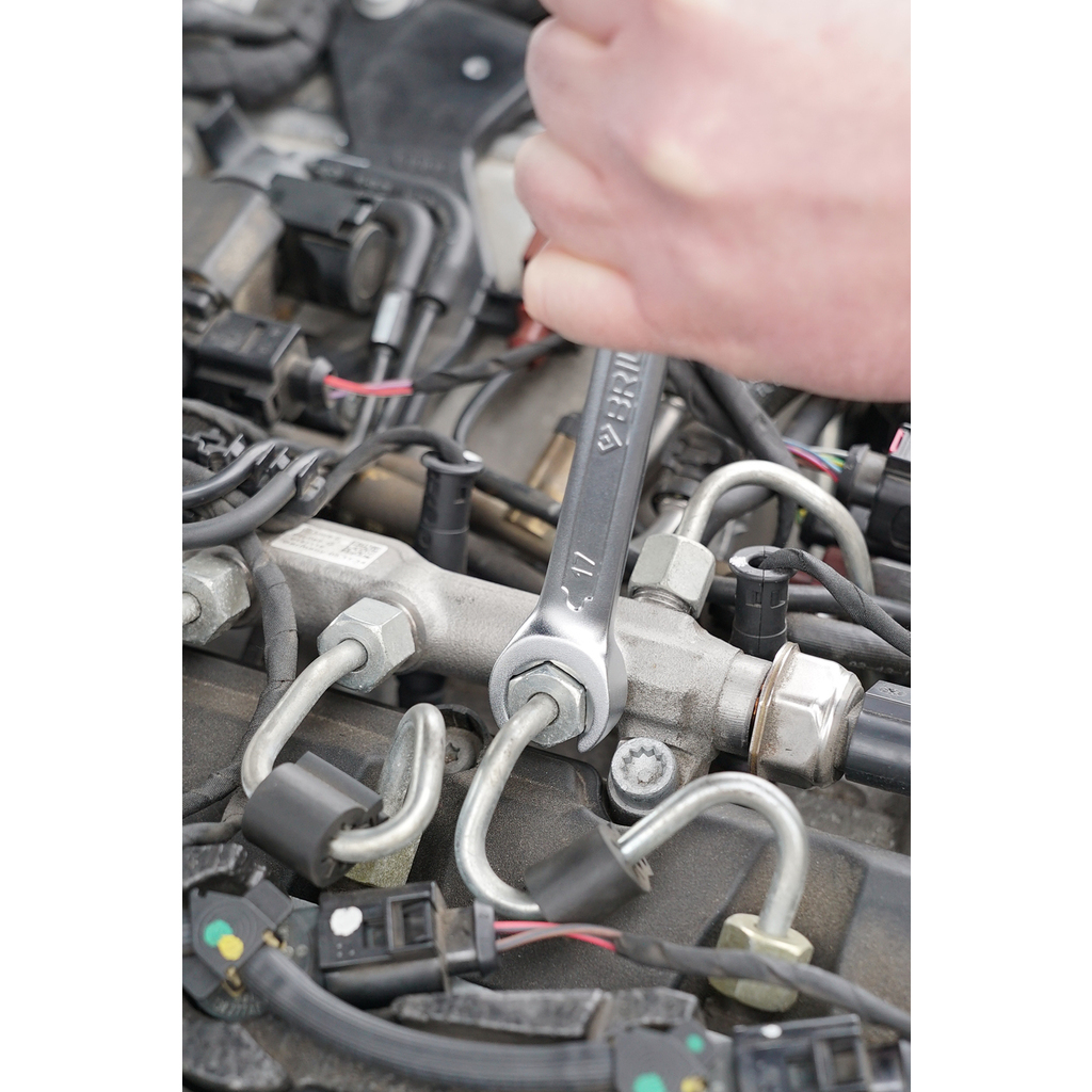 Eine Hand benutzt einen Schraubenschlüssel, um eine Mutter an einem Motor zu lösen.