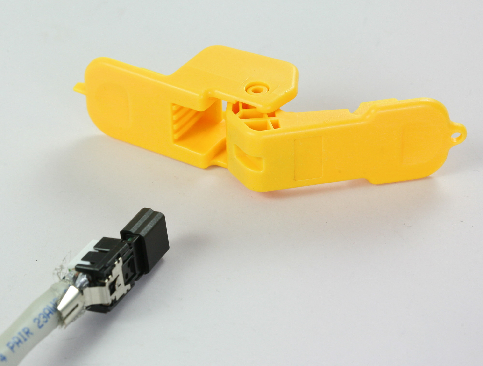 Ein gelber Plastikverbinder liegt neben einem Kabel mit einem schwarzen Stecker.
