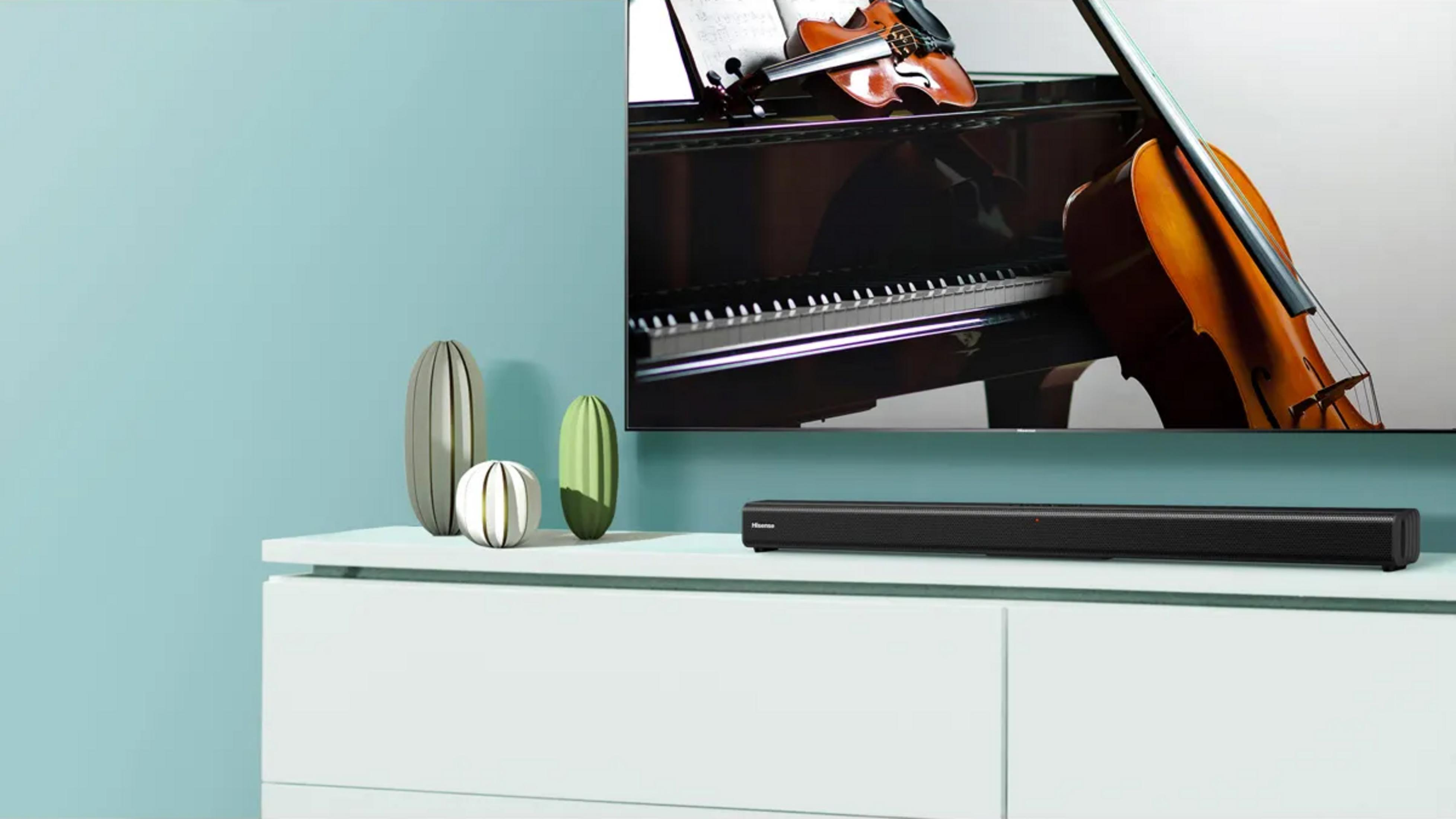 Ein Klavier, eine Geige und ein Cello auf einem Klavier. Auf der Kommode steht eine Soundbar.