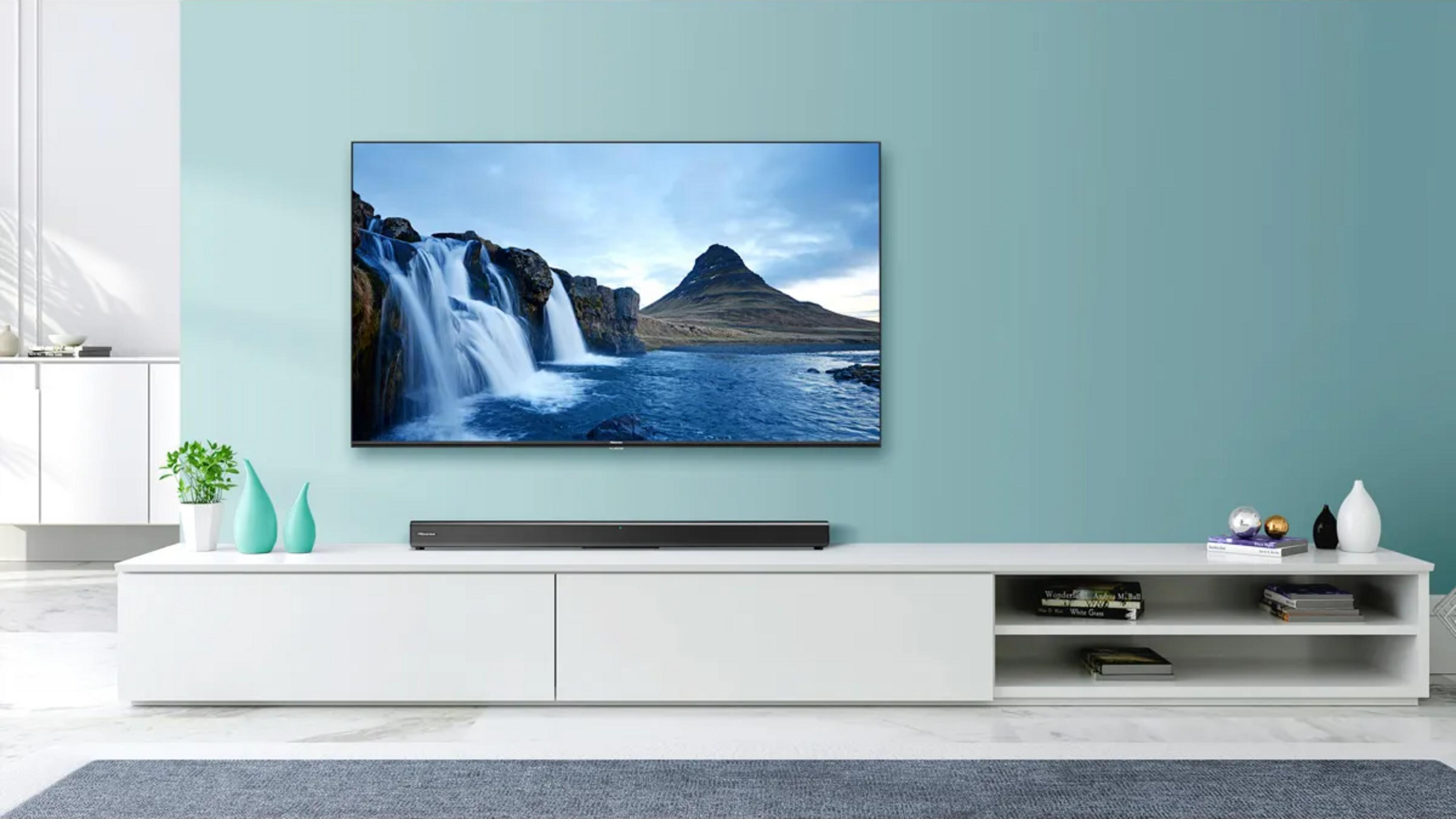 Ein Fernseher zeigt einen Wasserfall und Berg vor blauem Himmel. Ein TV-Schrank steht darunter.