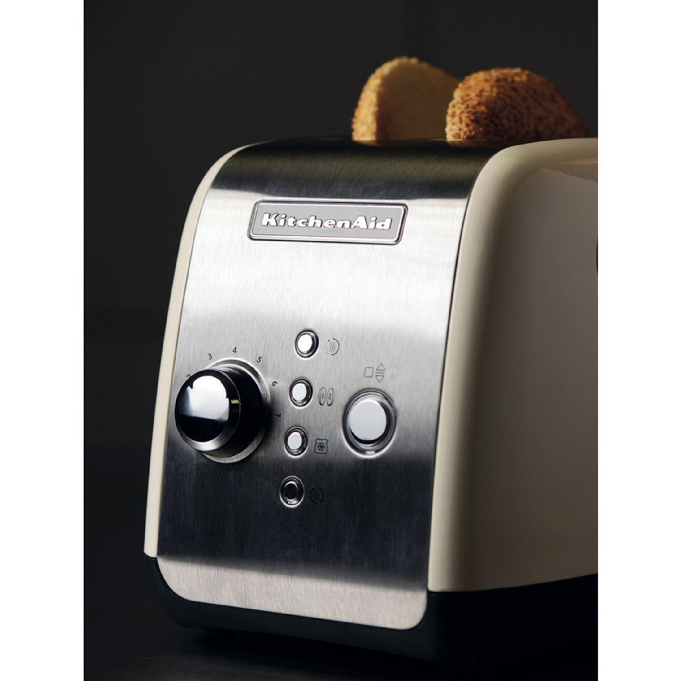 A cream-colored toaster with chrome accents and two slices of bread.