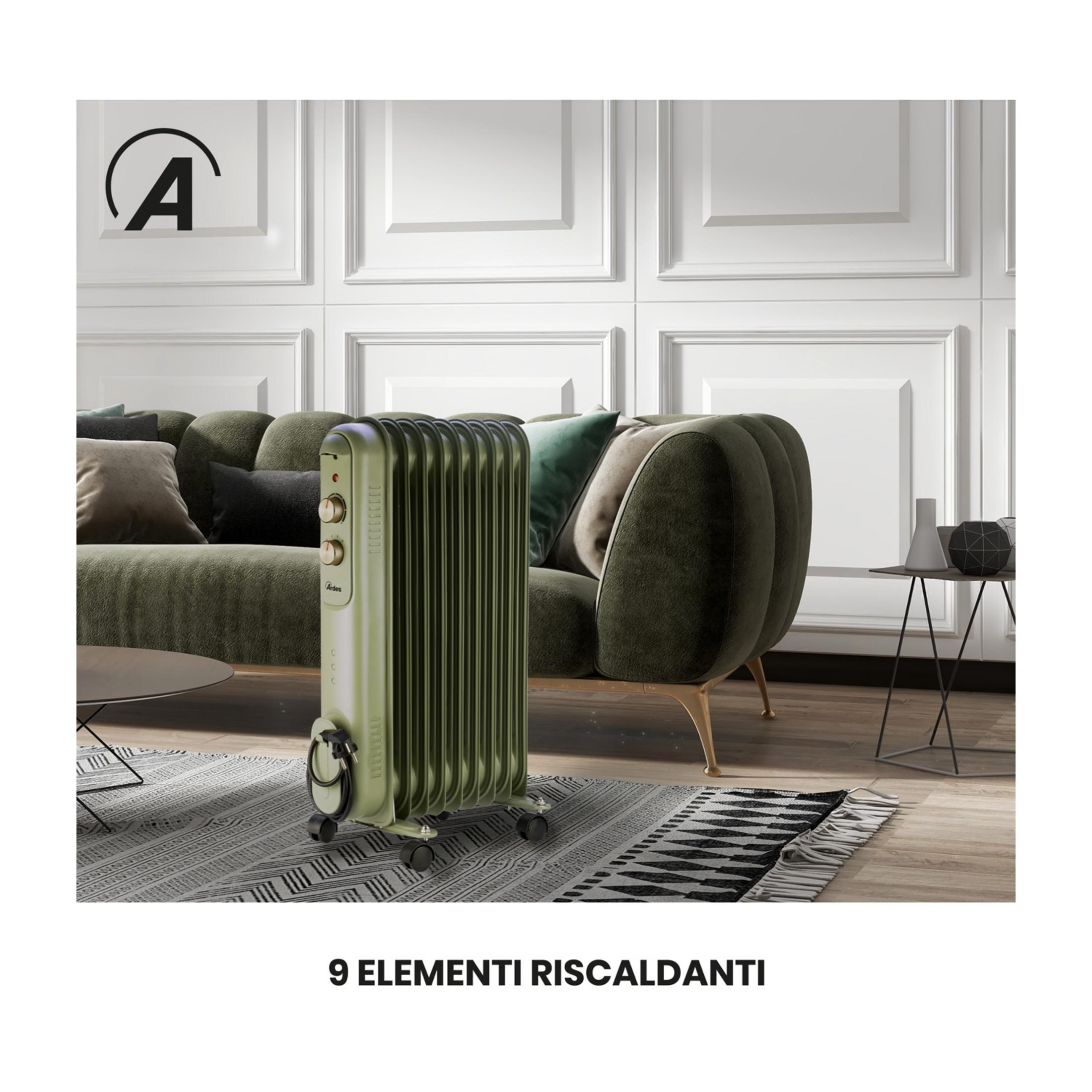 Zielony grzejnik olejowy stoi przed zieloną kanapą z poduszkami.