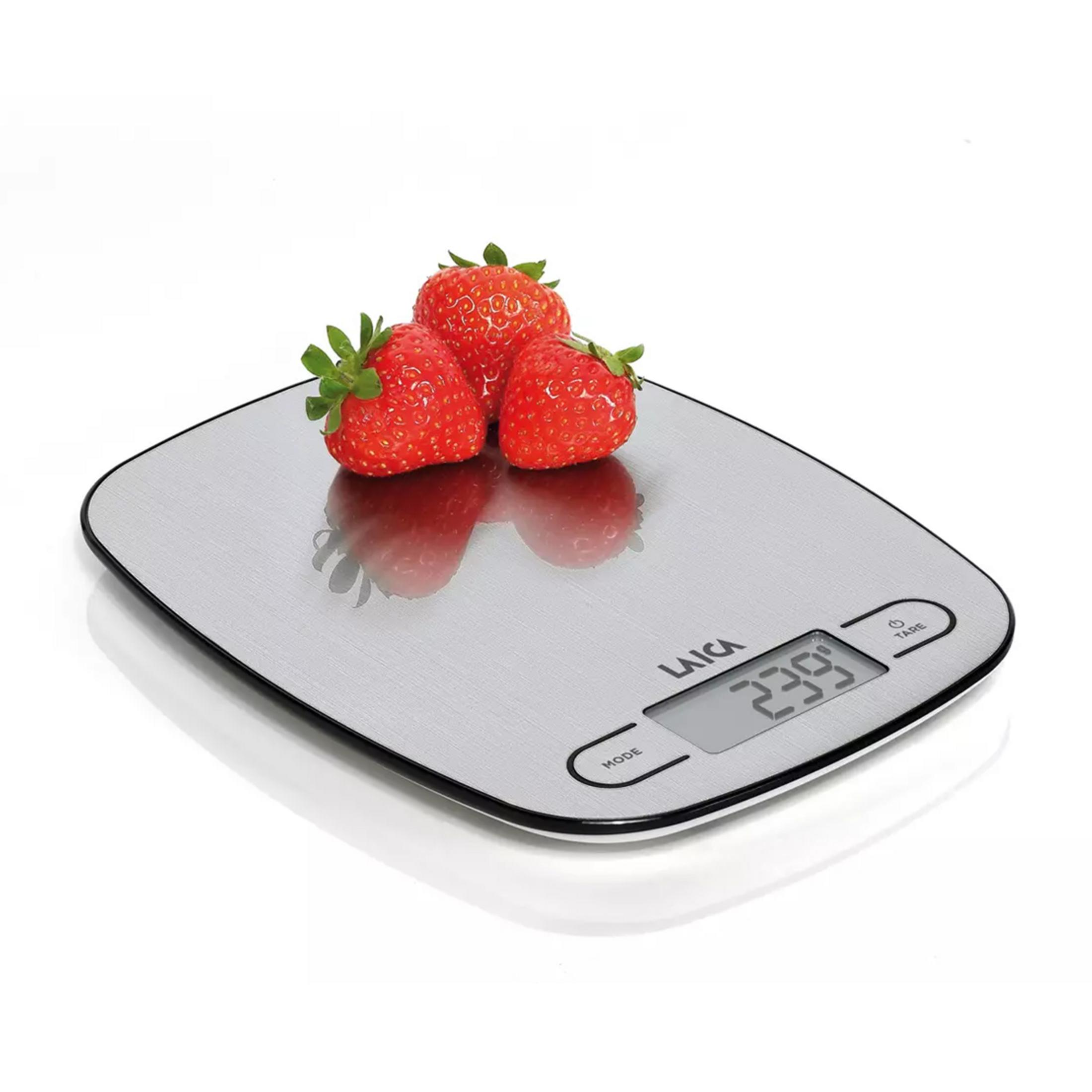 Three strawberries rest on a silver digital kitchen scale with a display showing 239.