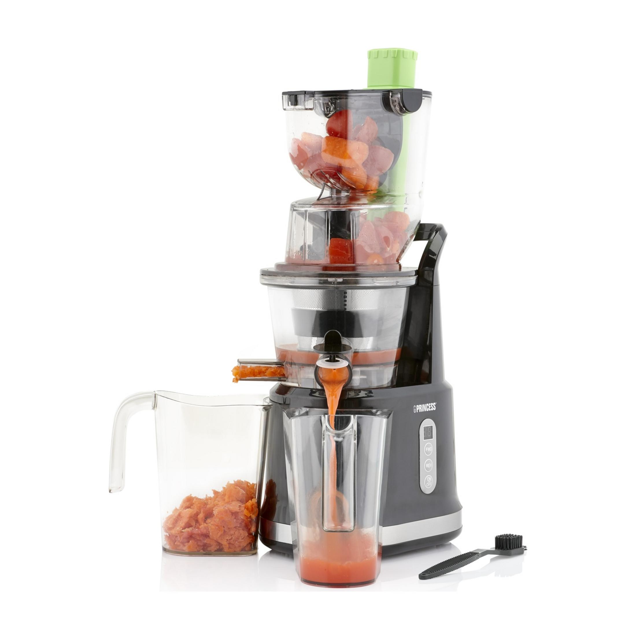 Une centrifugeuse avec des morceaux de fruits et du jus coulant dans un pichet.