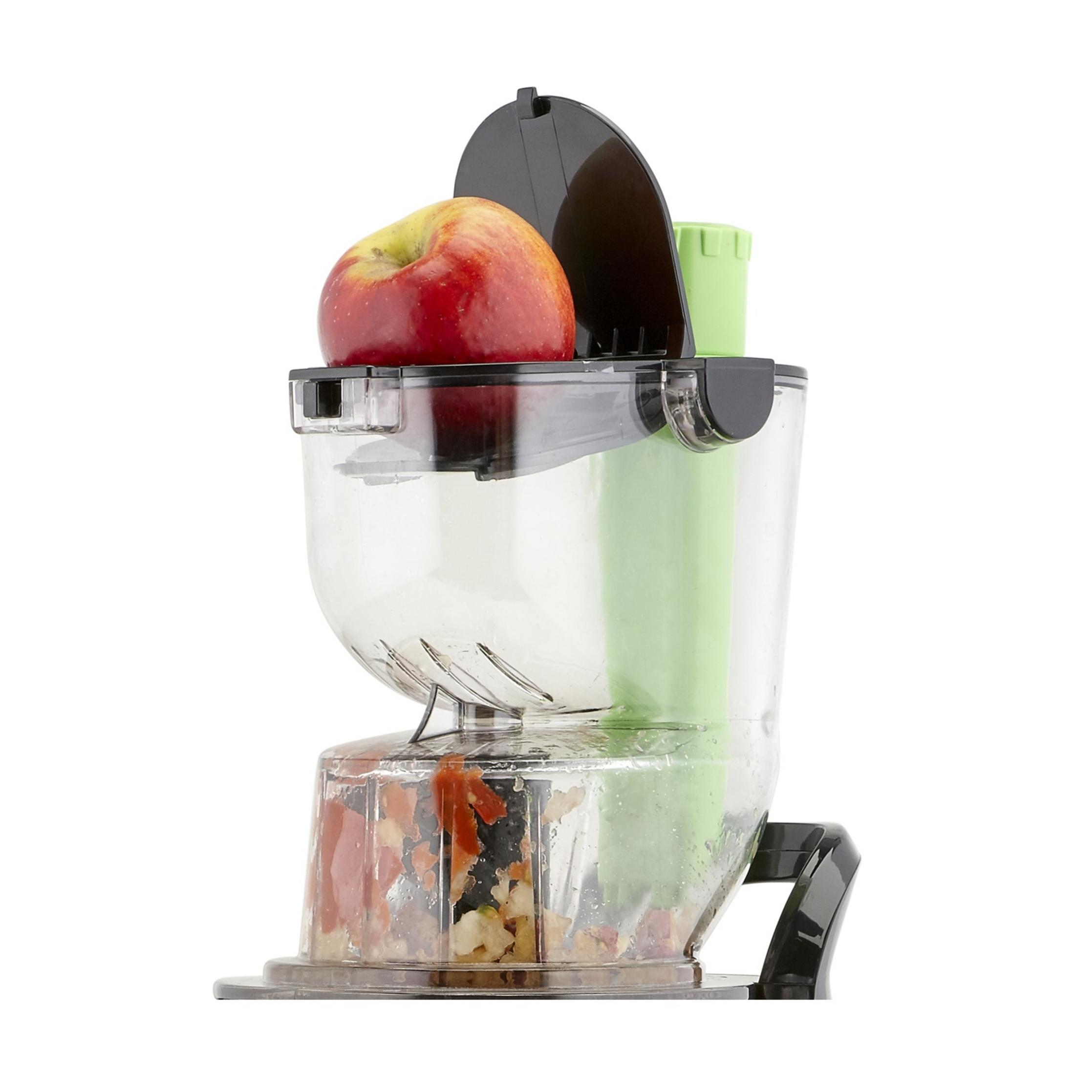 Une pomme rouge repose sur une centrifugeuse avec des fruits coupés dans le récipient.