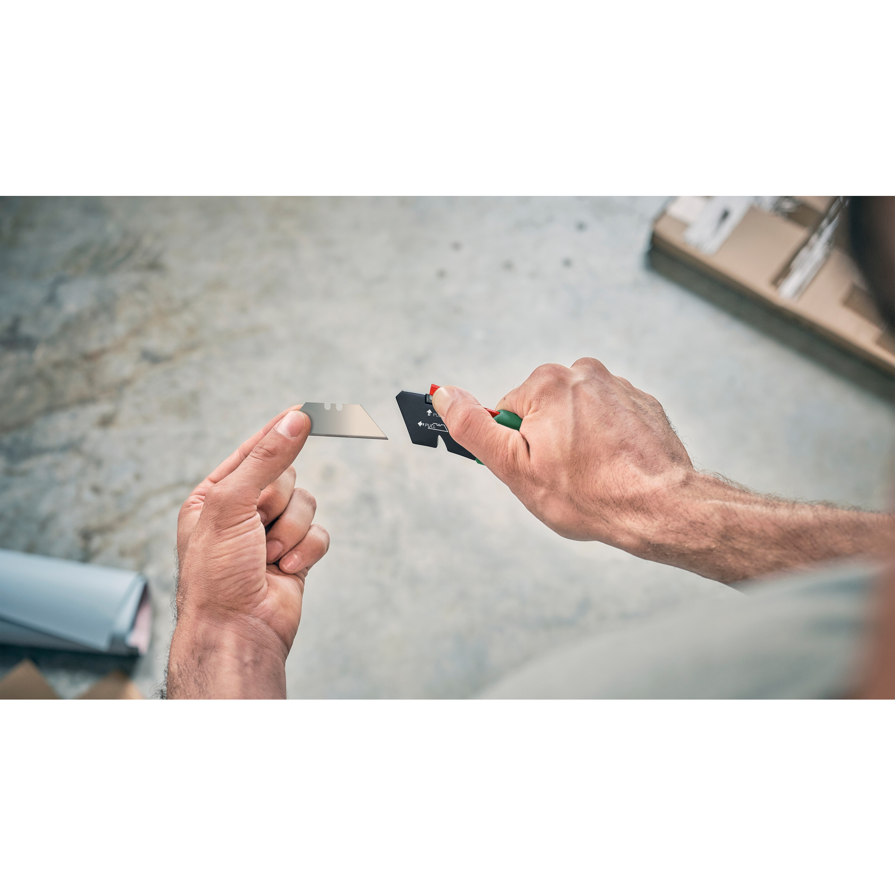 Person hält ein Cuttermesser und eine Ersatzklinge in den Händen.