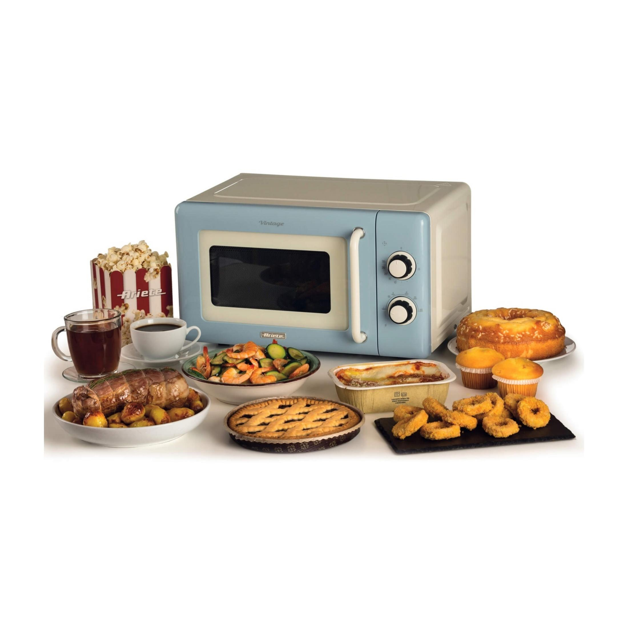 Niebieska kuchenka mikrofalowa vintage otoczona jedzeniem: pieczeń, ciasta, popcorn, kawa.