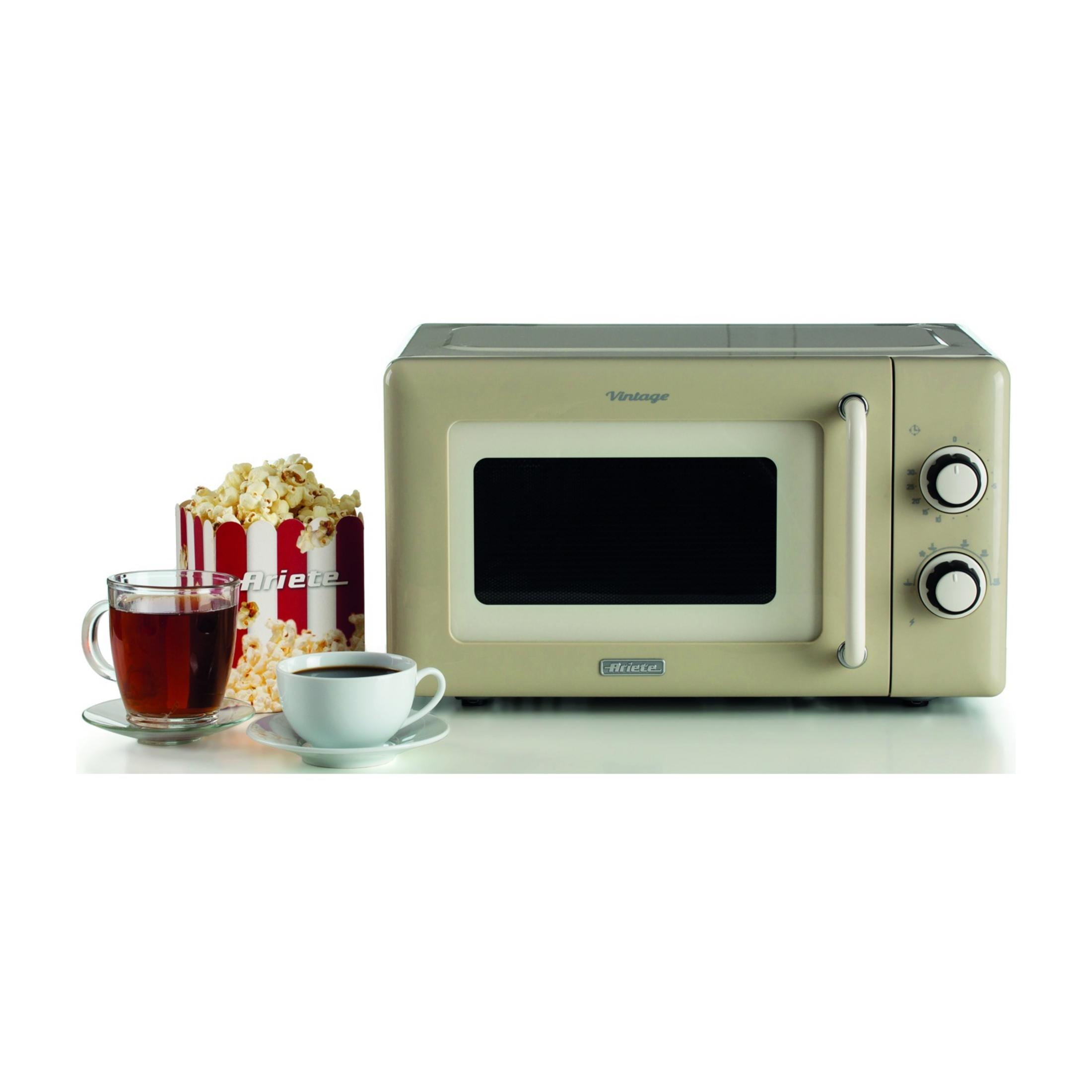 Kremowy, zabytkowy piekarnik mikrofalowy z popcornem i napojami obok.