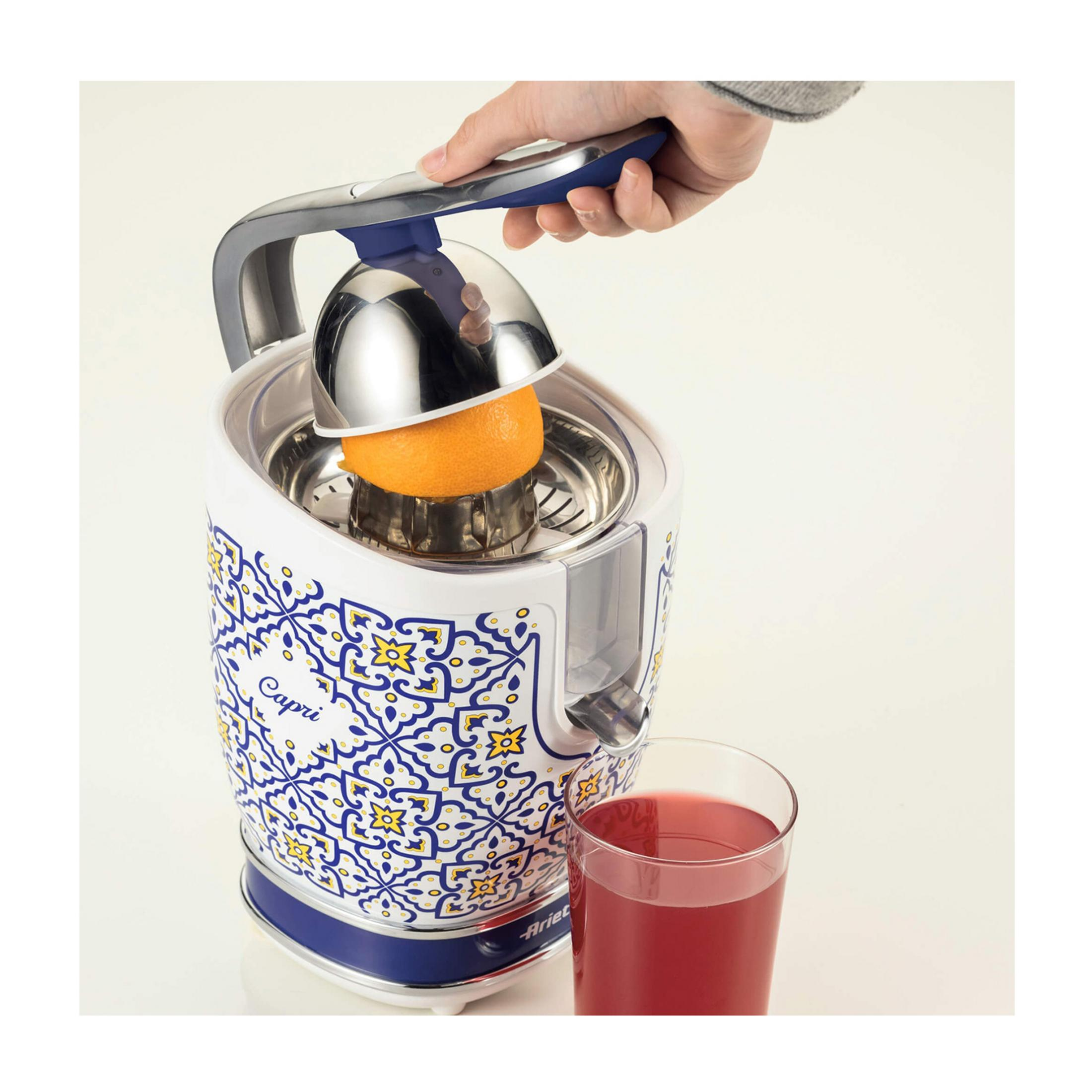 Ręka dociska pomarańczę do wyciskarki z niebiesko-żółtym wzorem.