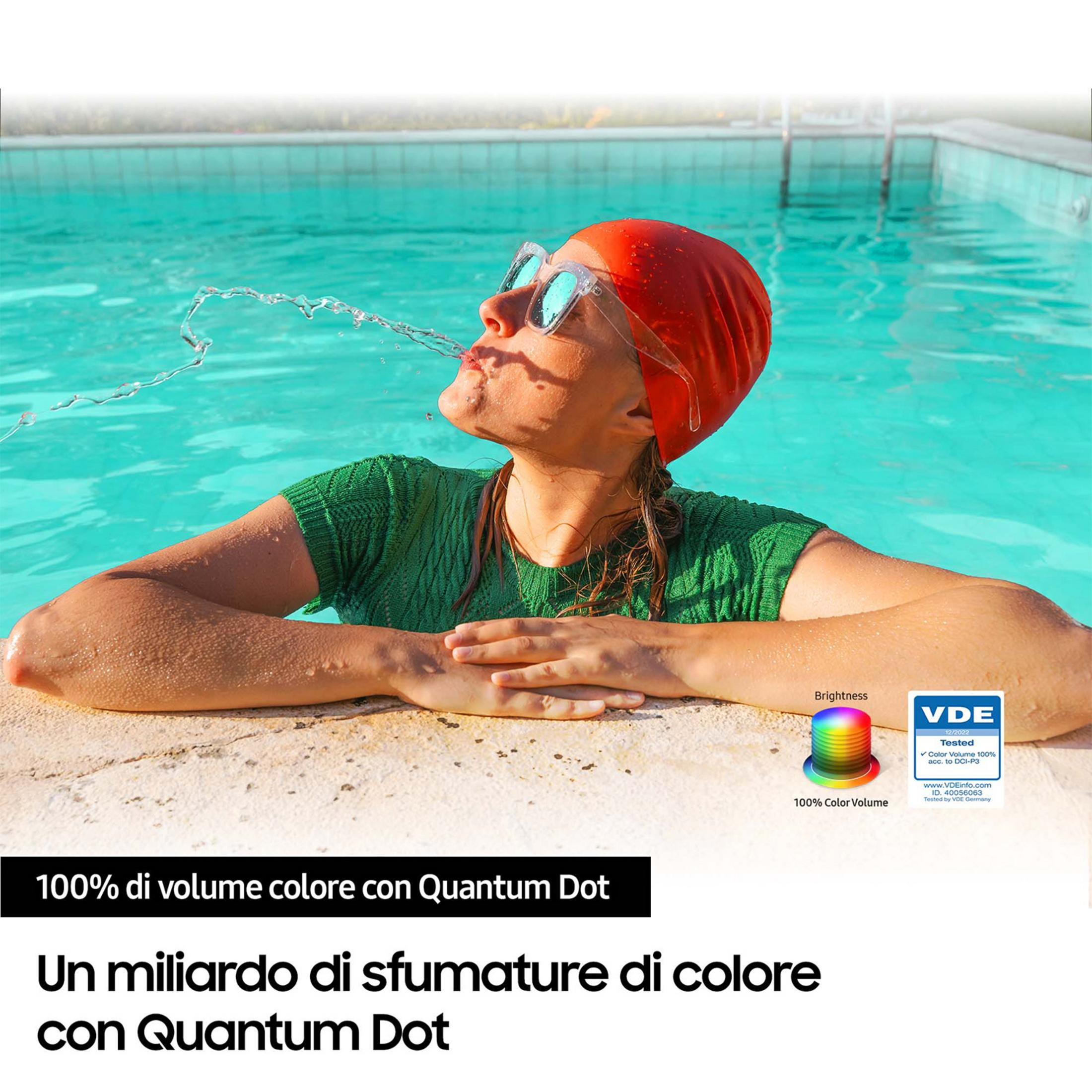 Donna con cuffia rossa schizza acqua in piscina, sigillo VDE indica 100% Volume Colore.