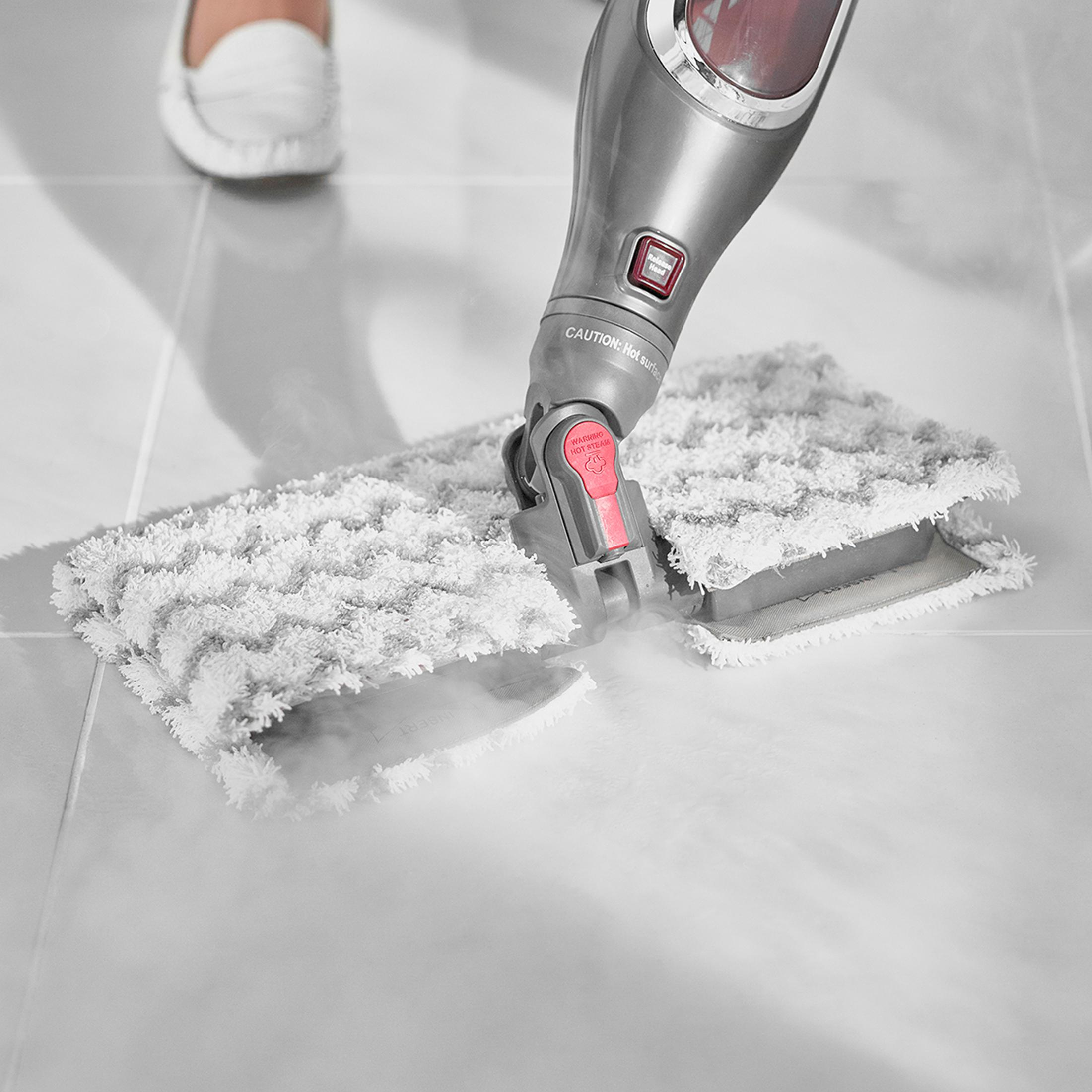 Mop parowy czyści płytki parą. Widoczna stopa w białym bucie.