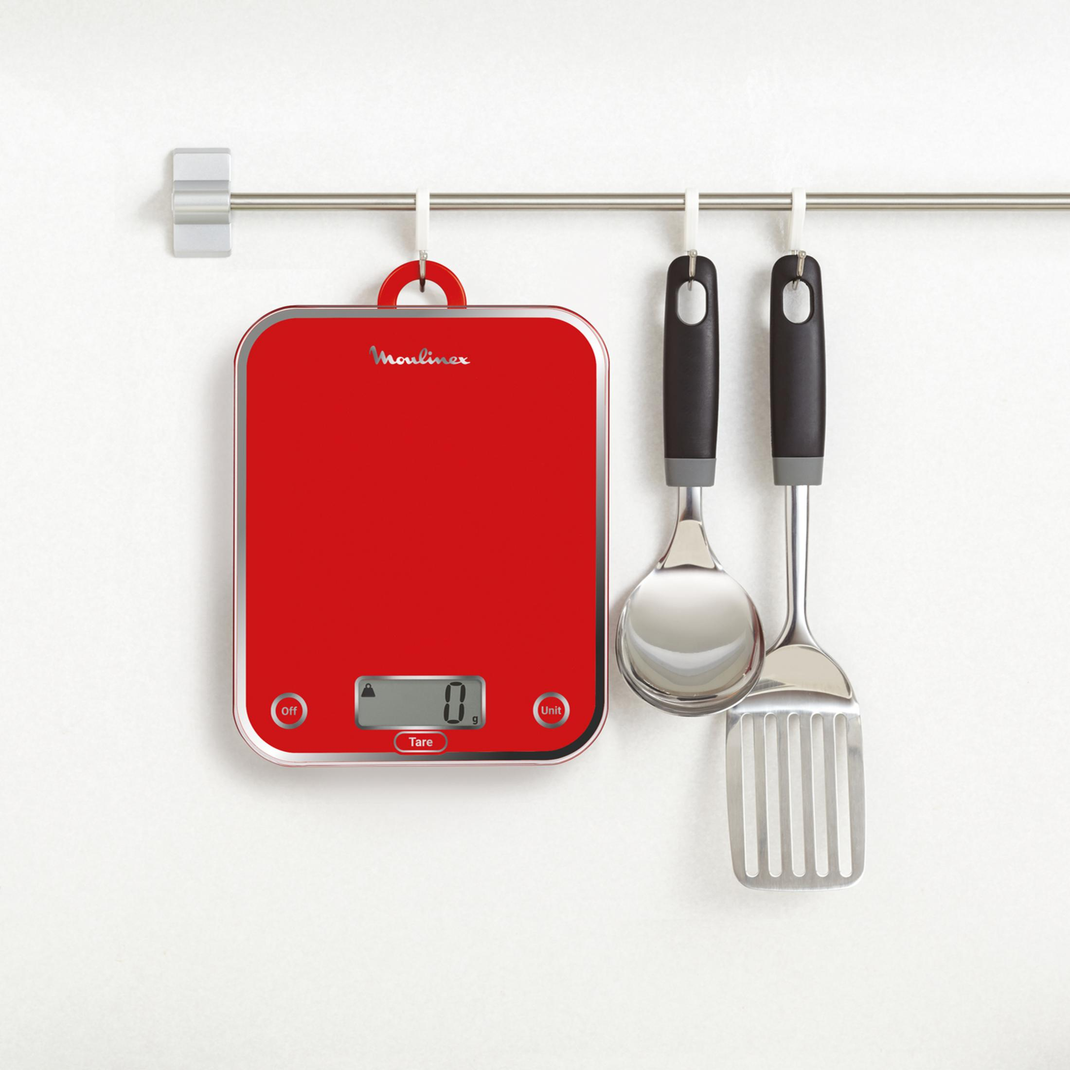 Una bilancia da cucina rossa con display digitale e due utensili appesi a una barra.