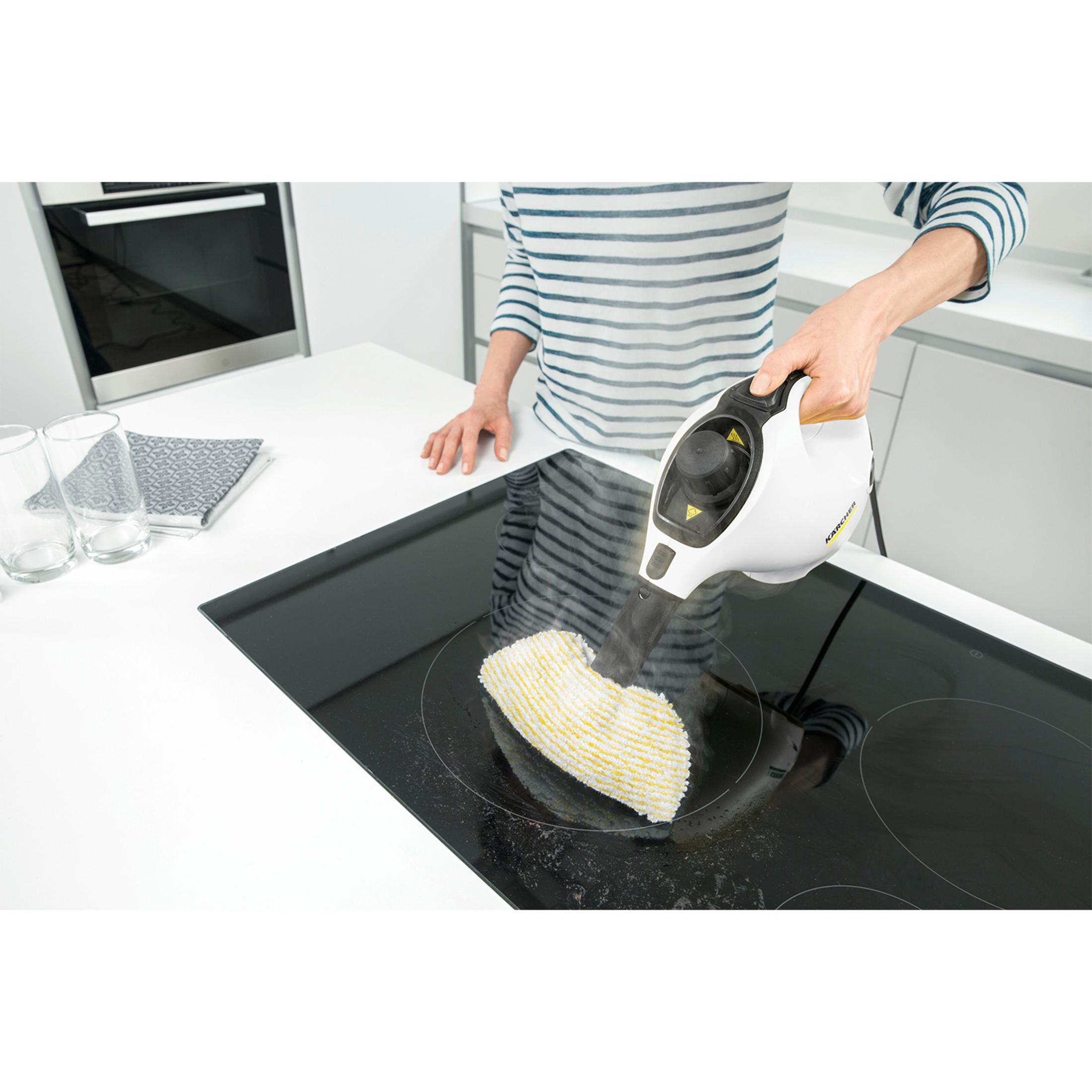 Osoba czyści płytę kuchenną parownicą.